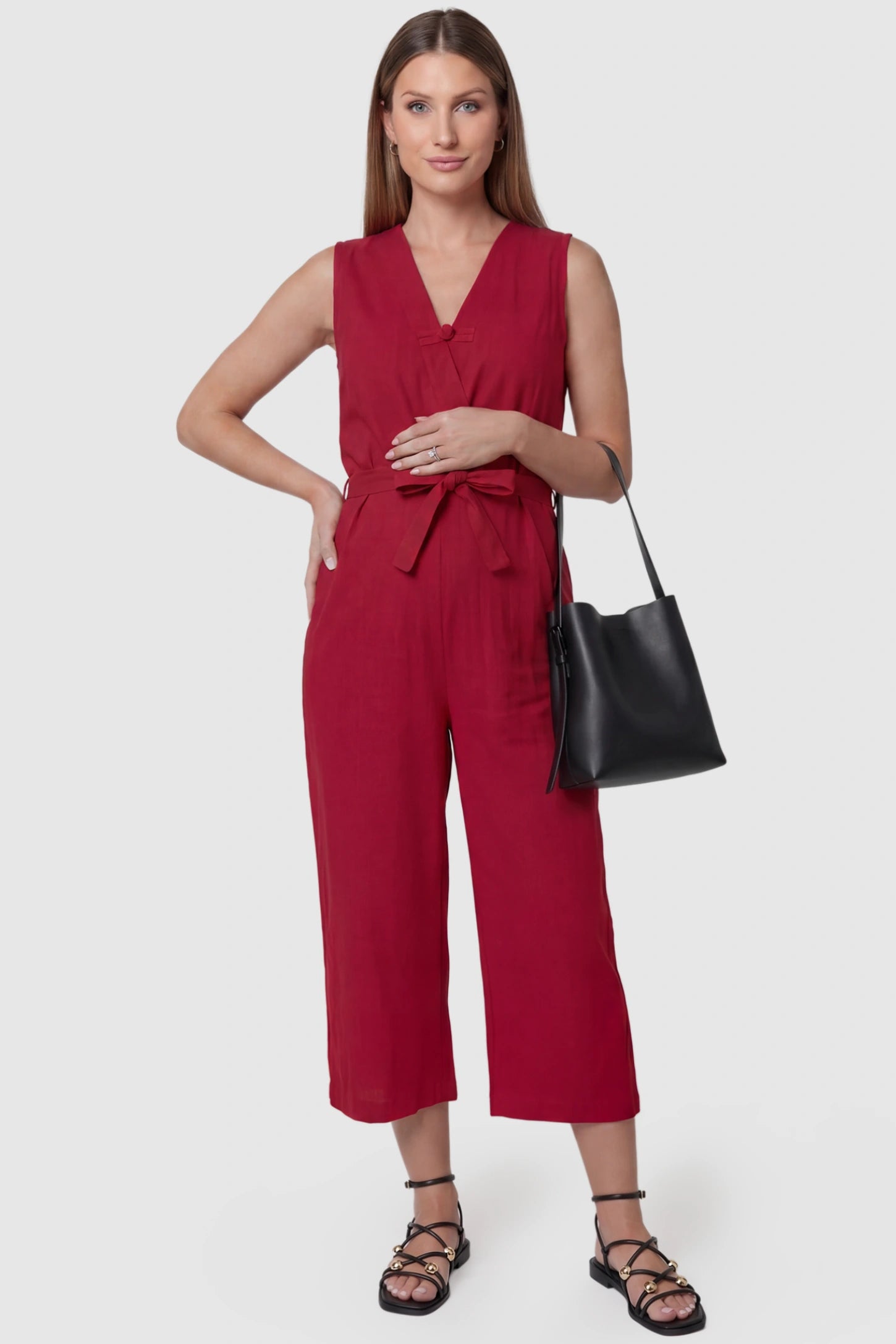 Sleeveless V-Neck Tie-Waist Maternity Jumpsuit Sleeveless V-Neck Tie-Waist Maternity Jumpsuit in Red featuring a relaxed wide-leg design on a pregnant model, front view.