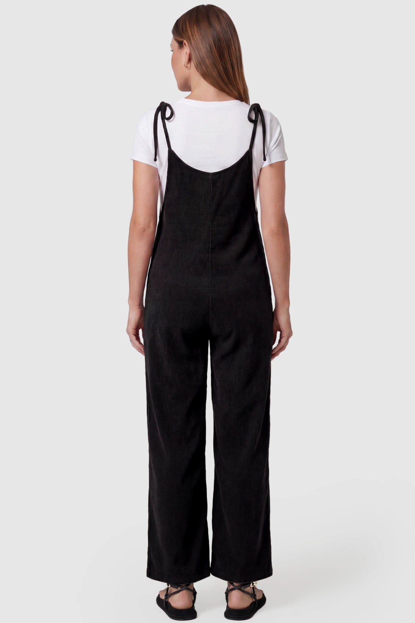 Solid Sleeveless Wide Leg Maternity Jumpsuit Solid Sleeveless Wide Leg Maternity Jumpsuit in Black featuring a flowy silhouette on a pregnant model, back view.