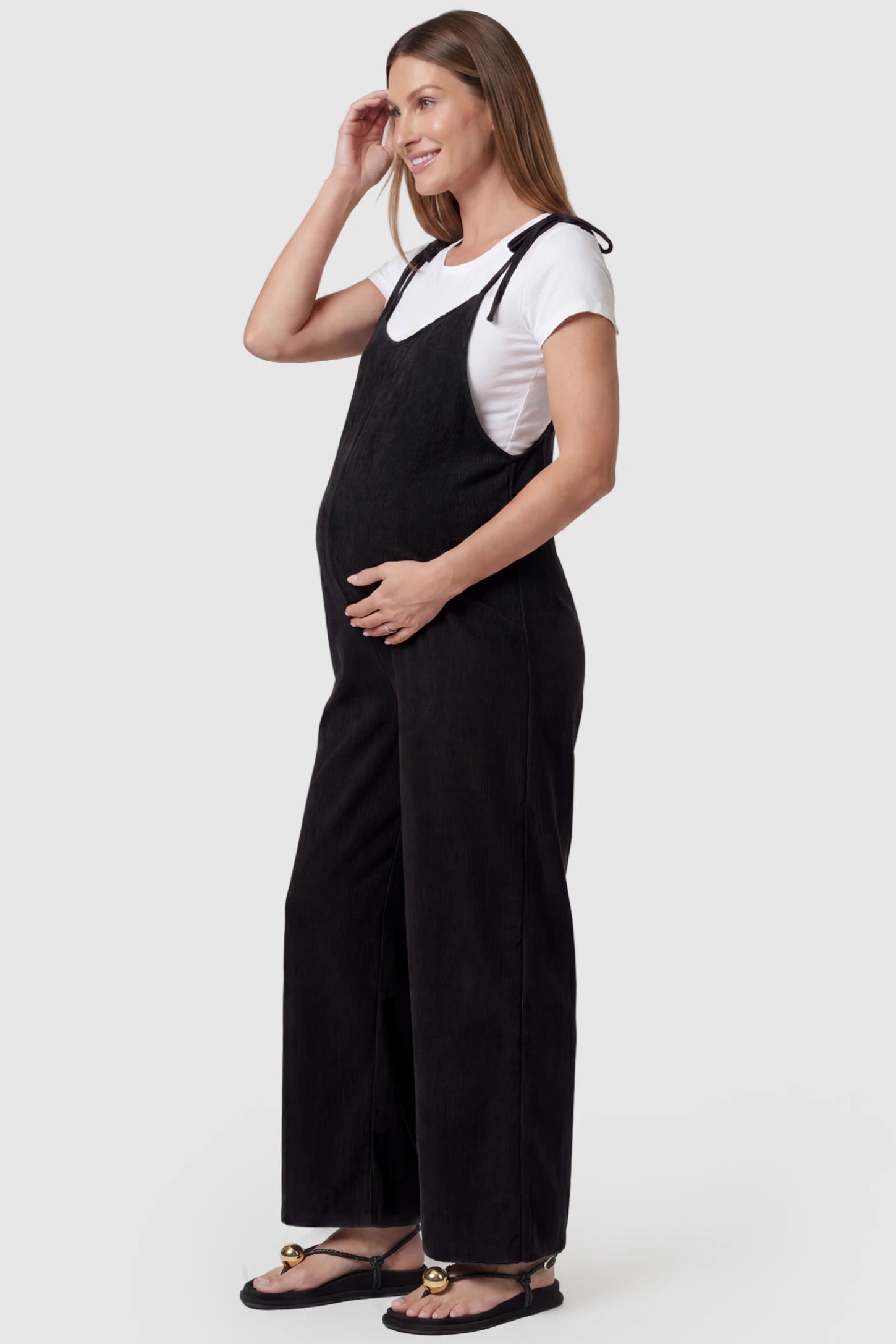 Solid Sleeveless Wide Leg Maternity Jumpsuit Solid Sleeveless Wide Leg Maternity Jumpsuit in Black featuring a flowy silhouette on a pregnant model, side view.