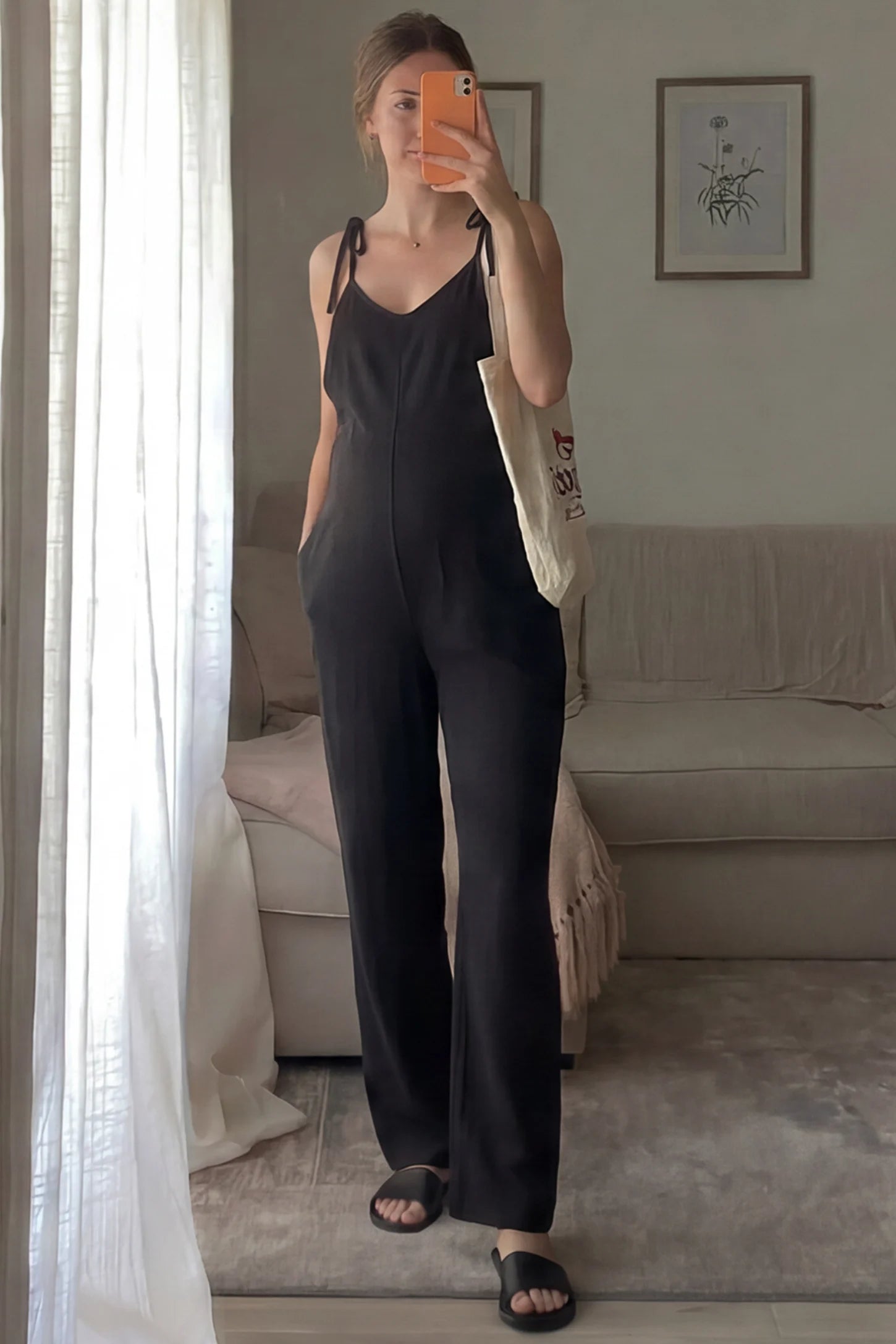 Solid Sleeveless Wide Leg Maternity Jumpsuit Solid Sleeveless Wide Leg Maternity Jumpsuit in Black featuring a flowy silhouette on a pregnant woman in an indoor setting, front view.