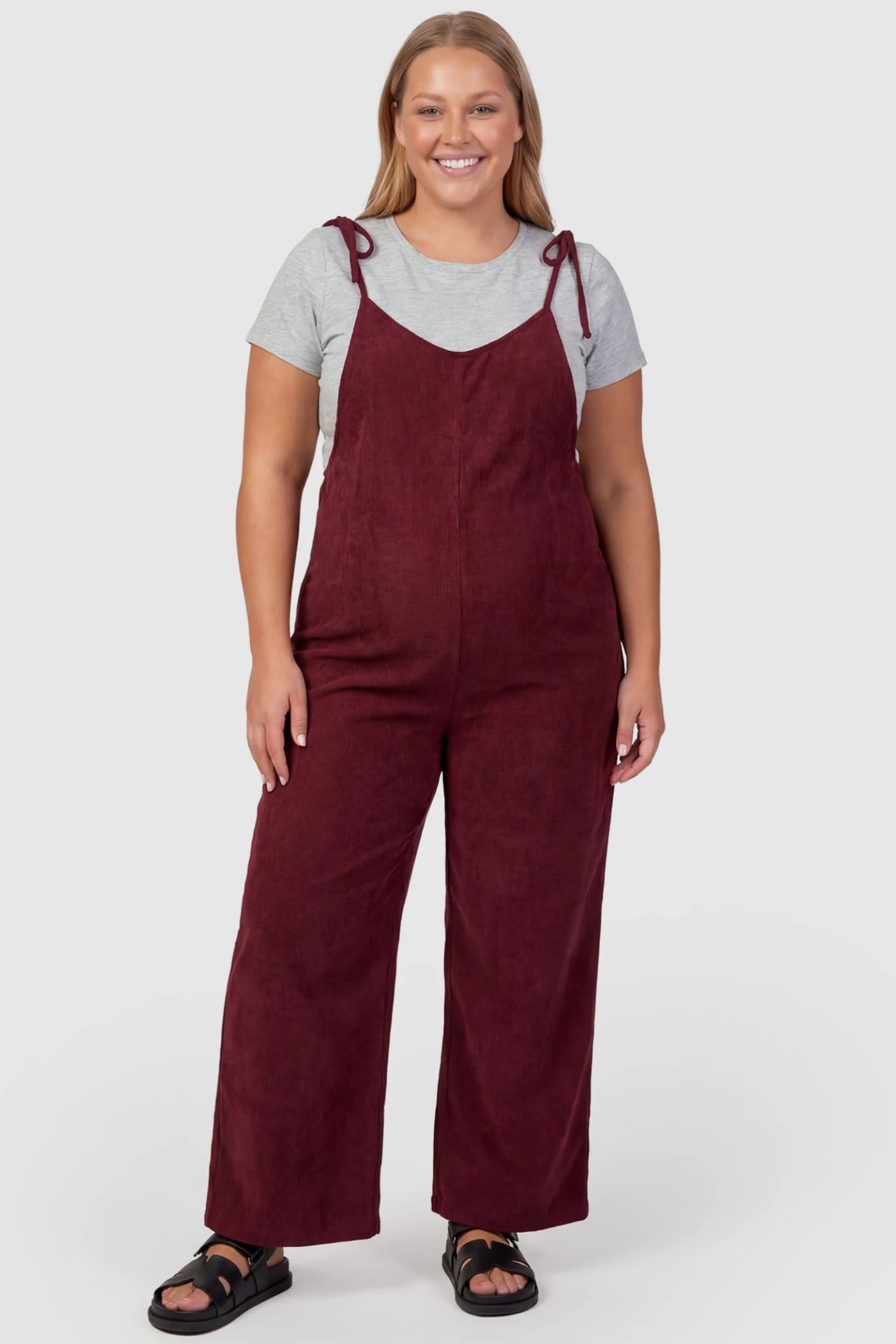Solid Sleeveless Wide Leg Maternity Jumpsuit Solid Sleeveless Wide Leg Maternity Jumpsuit in Wine Red featuring a flowy silhouette on a plus size pregnant model, front view.