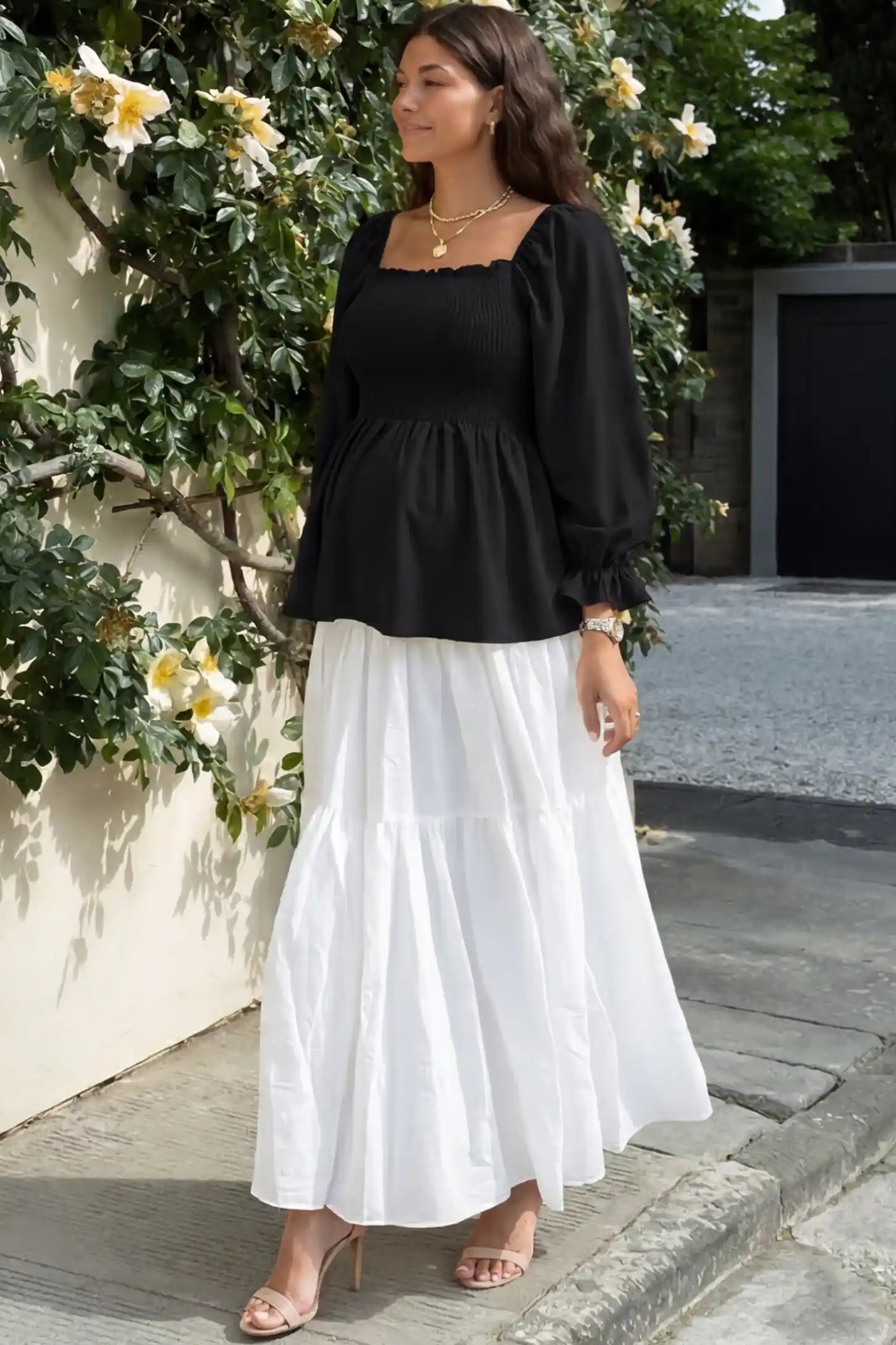 Smocked Convertible Neckline Bishop Sleeve Maternity Top Smocked Convertible Neckline Bishop Sleeve Maternity Top in Black featuring a smocked bodice on a pregnant model in an outdoor setting, front view.