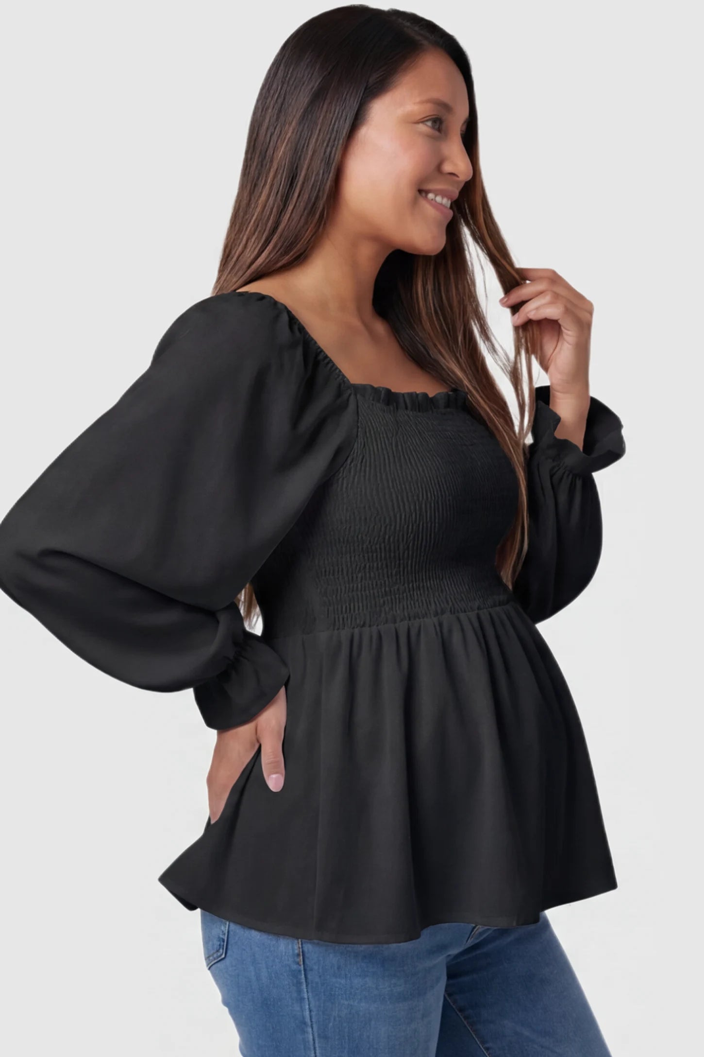 Smocked Convertible Neckline Bishop Sleeve Maternity Top Smocked Convertible Neckline Bishop Sleeve Maternity Top in Black featuring a peplum hem on a pregnant model side view.
