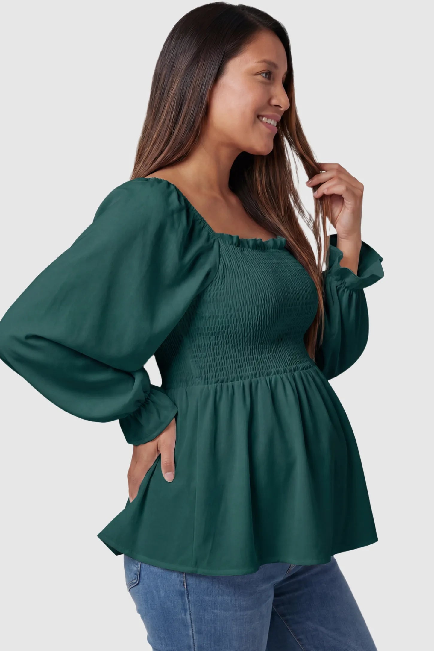 Smocked Convertible Neckline Bishop Sleeve Maternity Top in Green featuring a peplum hem on a pregnant model side view.
