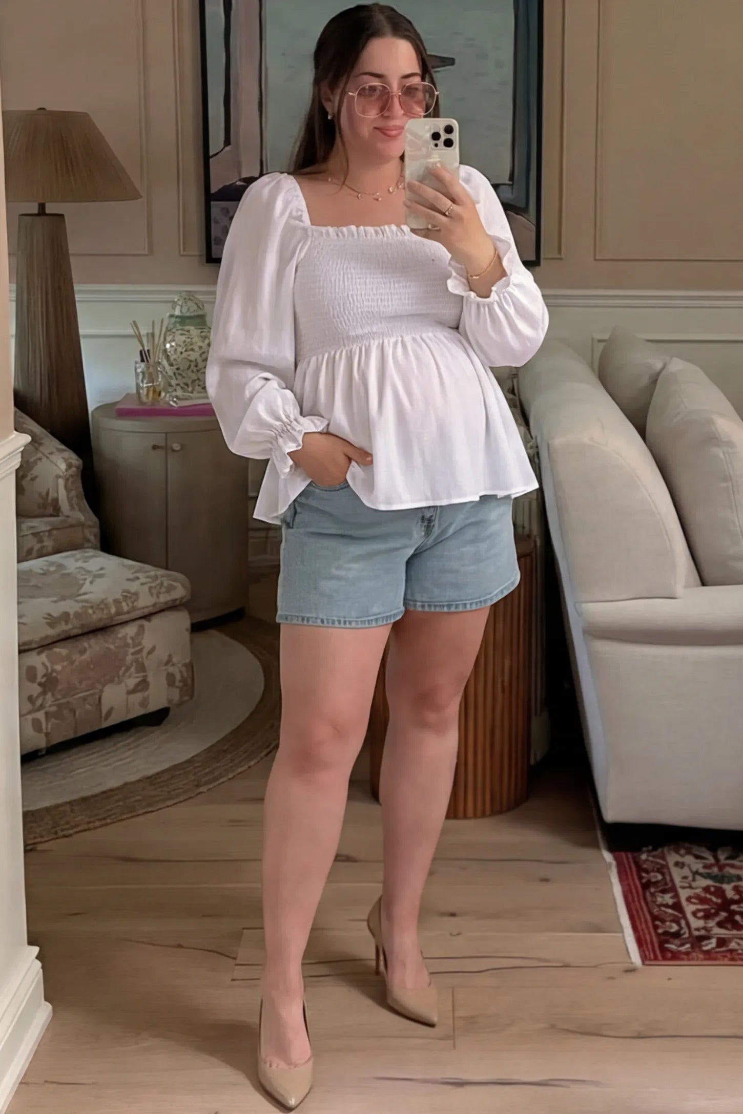 Smocked Convertible Neckline Bishop Sleeve Maternity Top Smocked Convertible Neckline Bishop Sleeve Maternity Top in White featuring a smocked bodice on a pregnant model in an outdoor setting, front view.