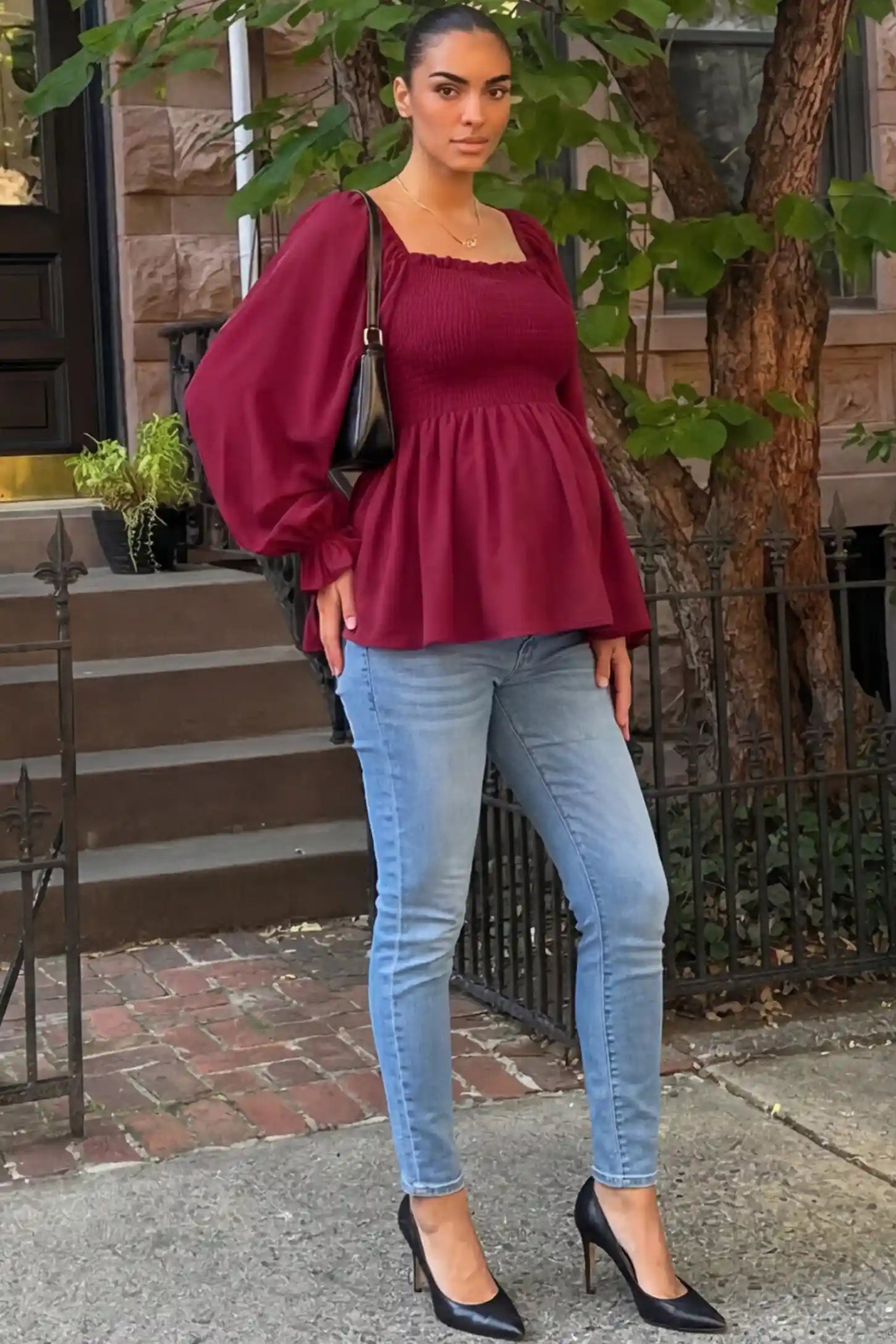 Smocked Convertible Neckline Bishop Sleeve Maternity Top Smocked Convertible Neckline Bishop Sleeve Maternity Top in Wine Red featuring a smocked bodice on a pregnant model in an outdoor setting, front view.