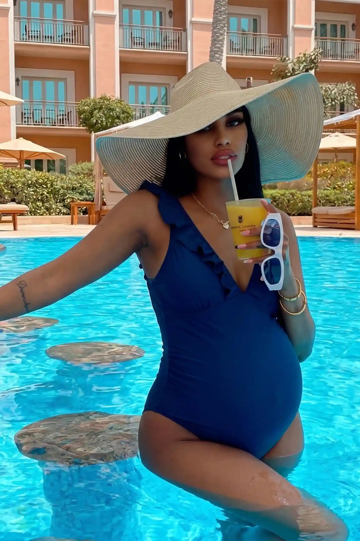 Smooth Matte Ruched Maternity One-Piece Swimsuit Smooth Matte Ruched Maternity One-Piece Swimsuit in Blue featuring elegant ruffles on a pregnant model in a resort setting.