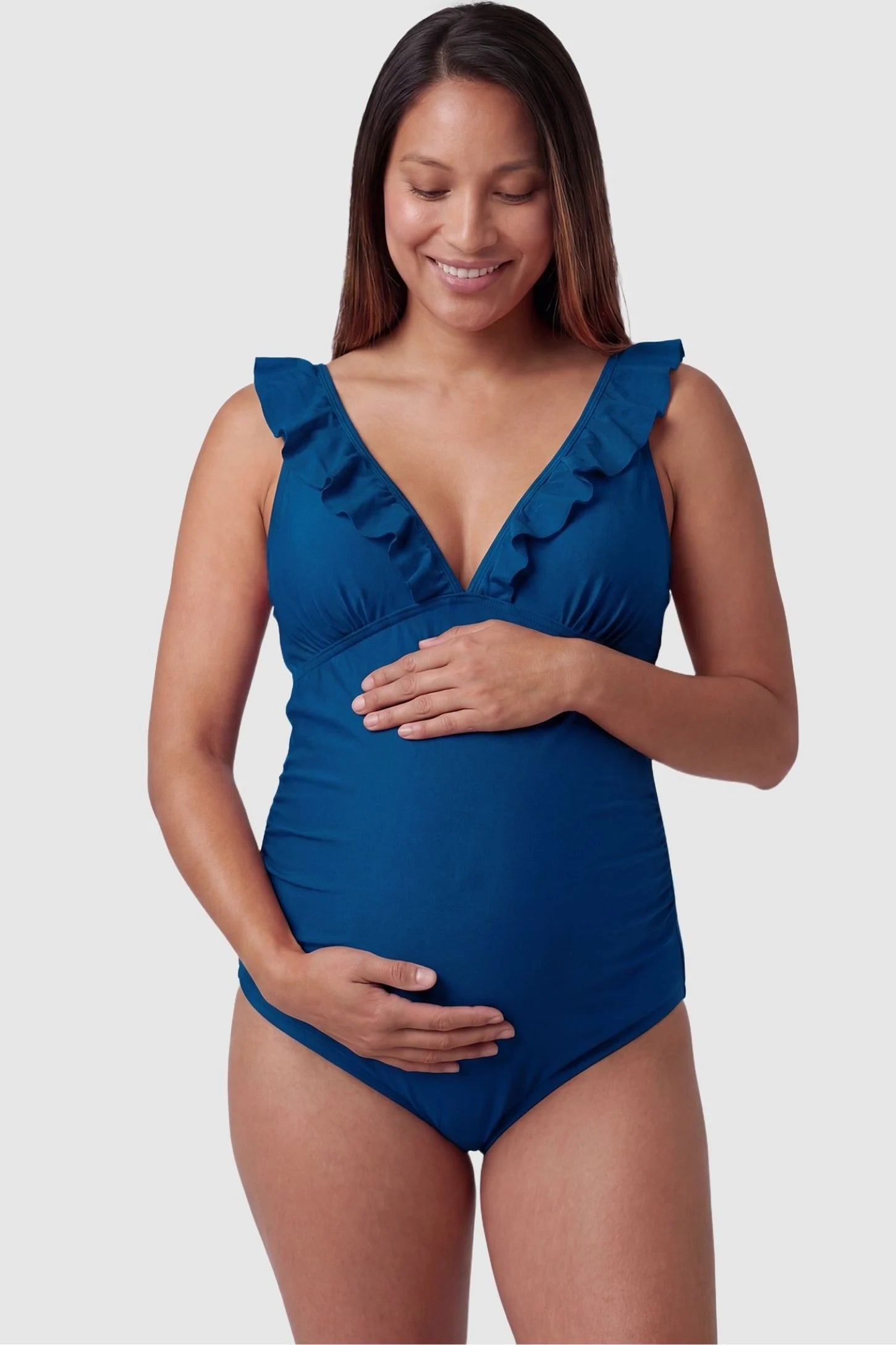 Smooth Matte Ruched Maternity One-Piece Swimsuit Smooth Matte Ruched Maternity One-Piece Swimsuit in Blue featuring ruffle straps and a V-neck front on a pregnant model, front view.