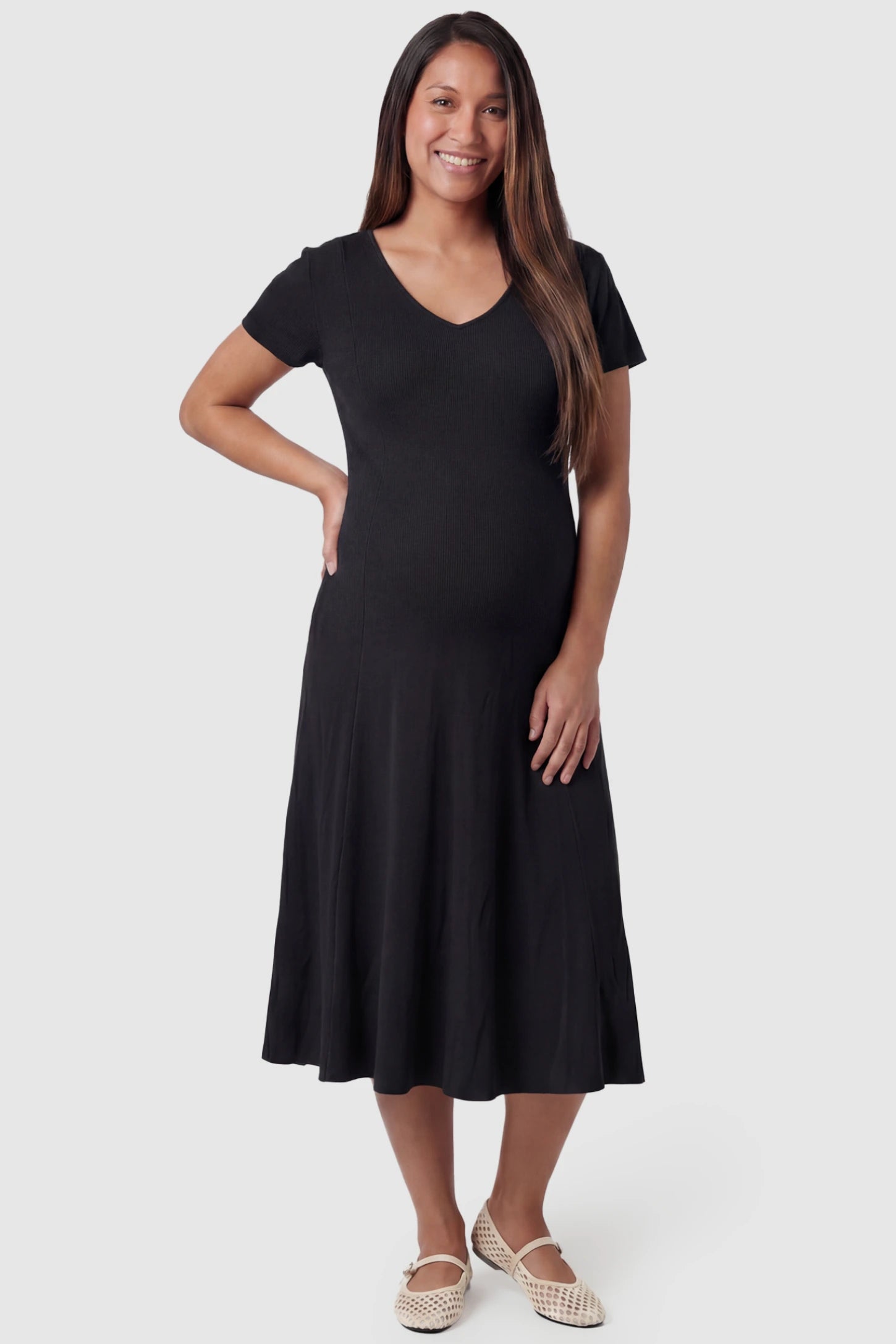 Soft Knit Stretch Short Sleeve Maternity Midi Dress Soft Knit Stretch Short Sleeve Maternity Midi Dress in Black featuring a flattering v-neck and high stretch knit on a pregnant model, front view.