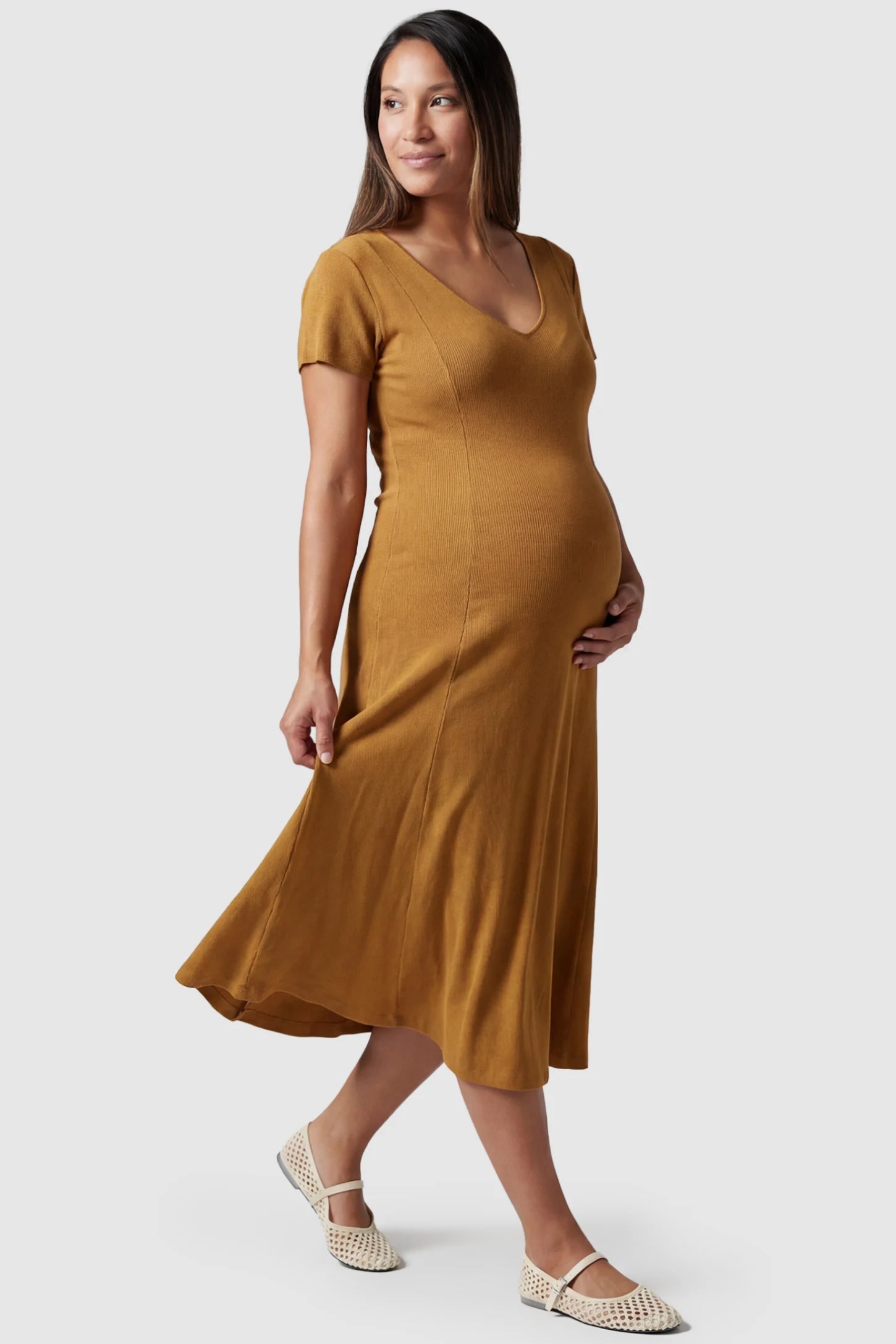 Soft Knit Stretch Short Sleeve Maternity Midi Dress Soft Knit Stretch Short Sleeve Maternity Midi Dress in Camel featuring a flattering v-neck and high stretch knit on a pregnant model, side view.