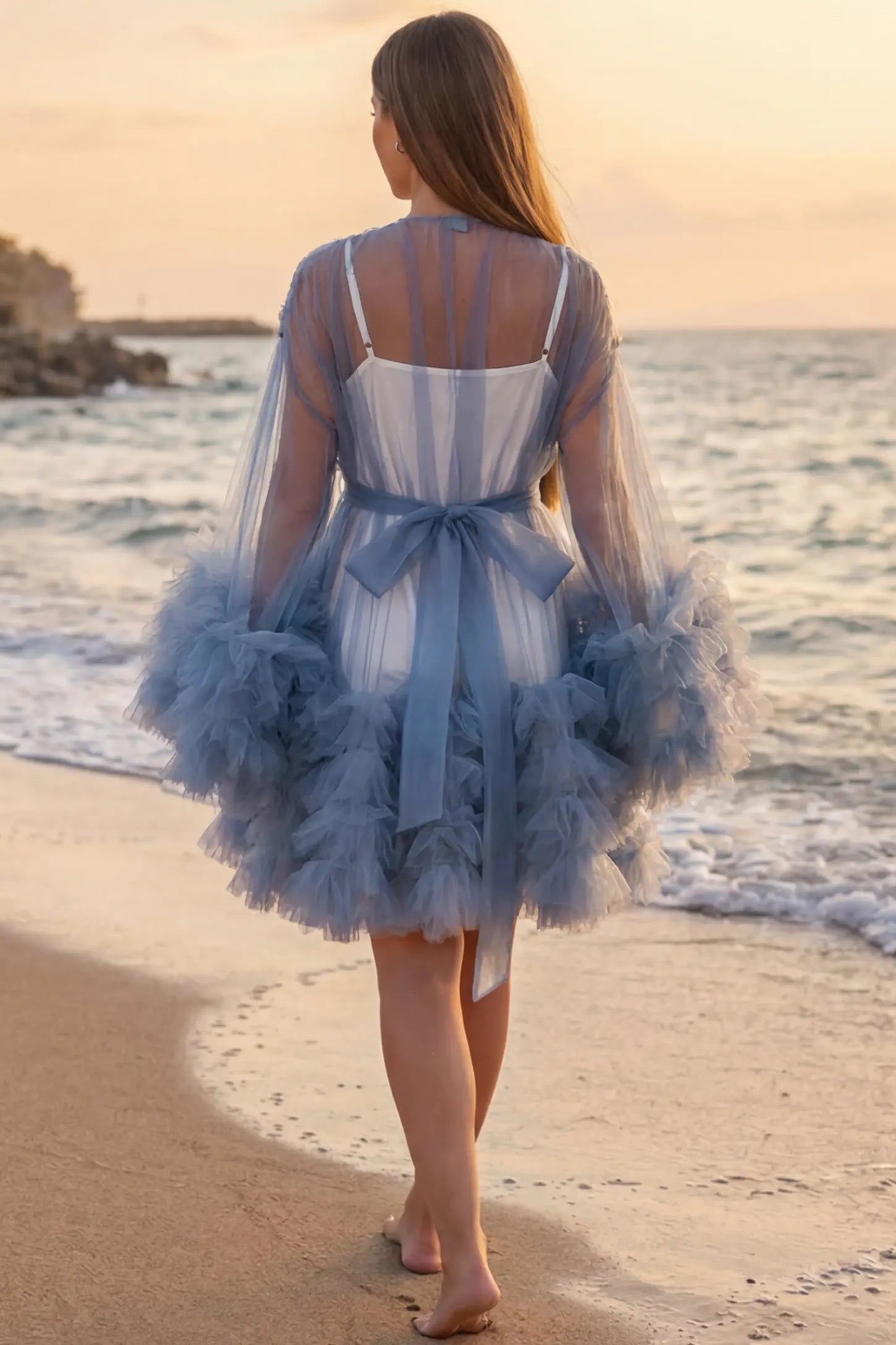 Soft Nylon Mesh Long Sleeve Maternity Photoshoot Dress Soft Nylon Mesh Long Sleeve Maternity Photoshoot Dress in Blue featuring a tied bow waist on a pregnant model at the beach, back view.