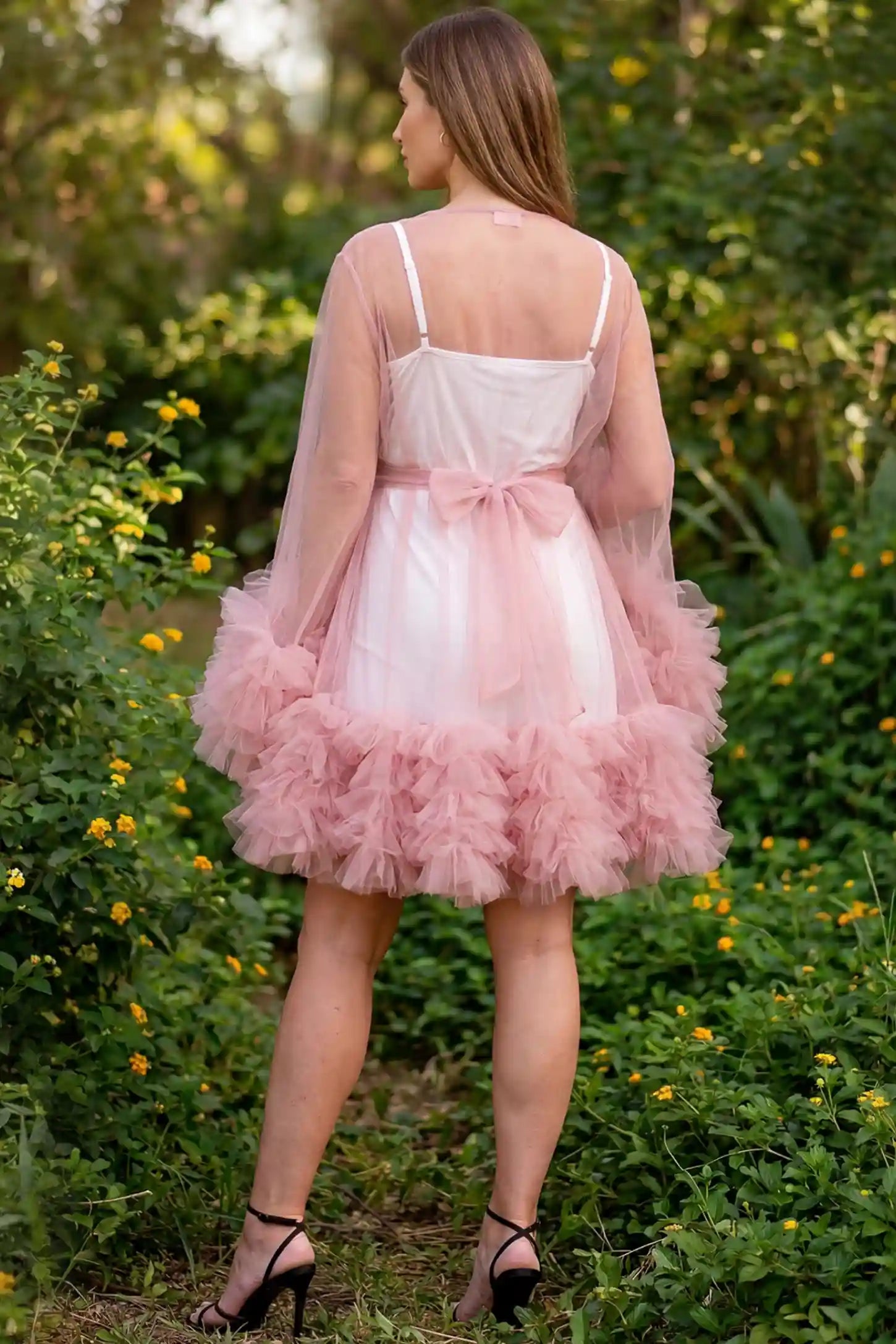Soft Nylon Mesh Long Sleeve Maternity Photoshoot Dress Soft Nylon Mesh Long Sleeve Maternity Photoshoot Dress in Pink featuring a tied bow waist on a pregnant model in a garden, back view.