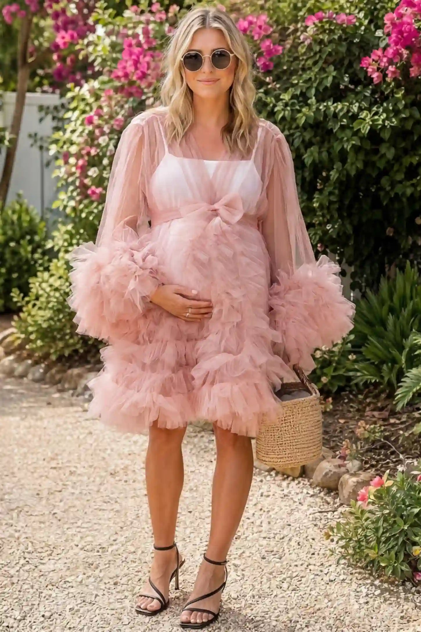 Soft Nylon Mesh Long Sleeve Maternity Photoshoot Dress Soft Nylon Mesh Long Sleeve Maternity Photoshoot Dress in Pink featuring sheer V-neck, ruffle trim layered hem on a pregnant model in a garden, front view.