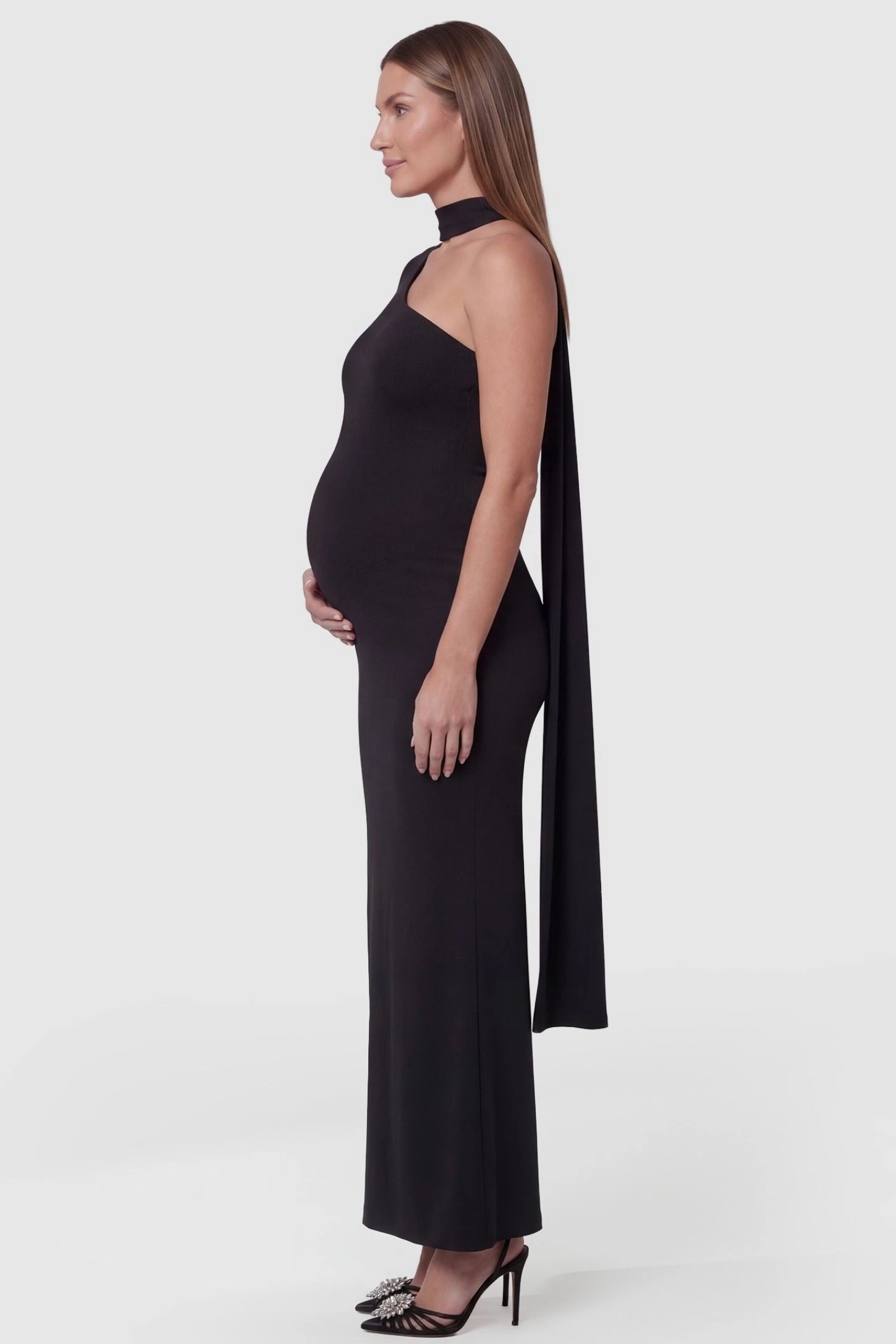 Soft Stretch One-Sleeve Halter Maternity Dress Black Soft Stretch One-Sleeve Halter Maternity Dress featuring a dramatic cape-sleeve on a pregnant model side view.