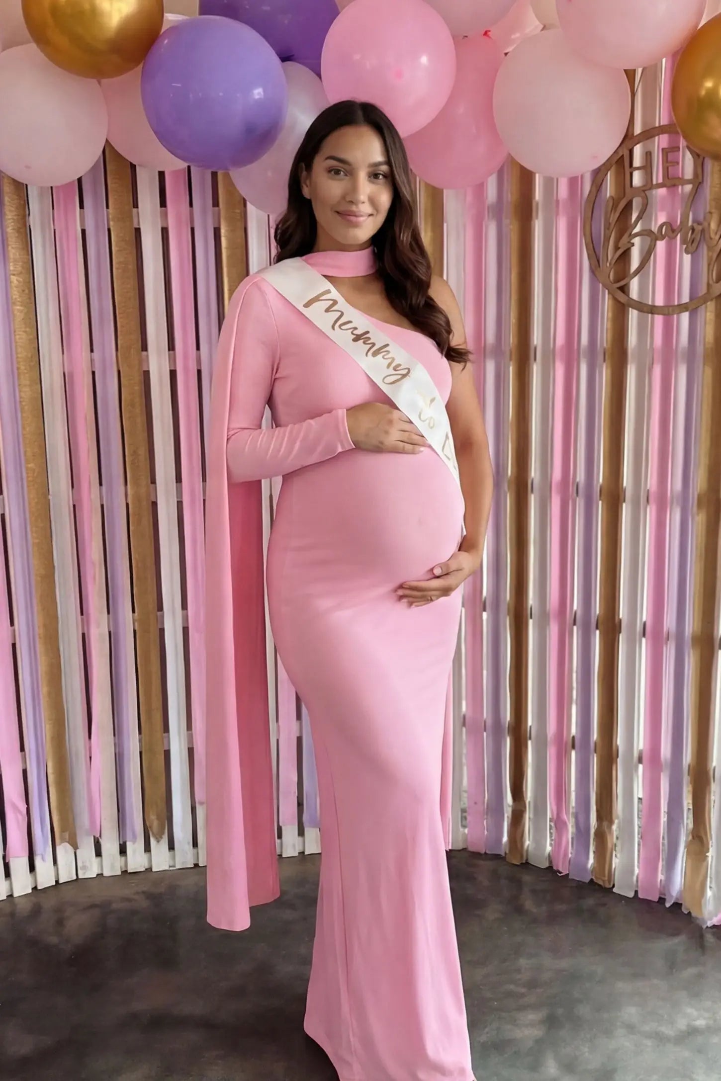 Soft Stretch One-Sleeve Halter Maternity Dress Soft Stretch One-Sleeve Halter Maternity Dress in Pink featuring a sophisticated one-arm sleeve on a pregnant model.