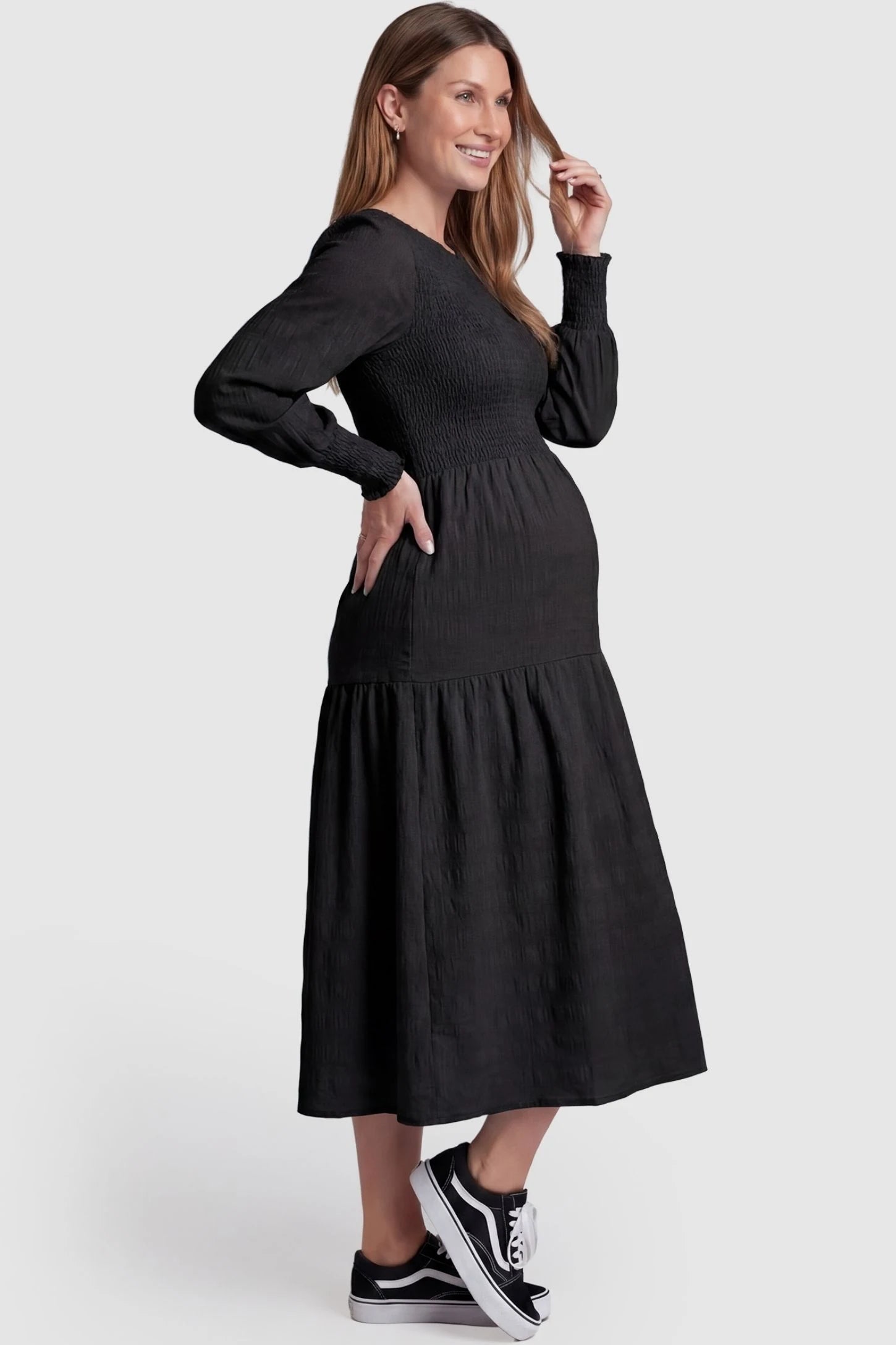 Solid Color Tiered Style Midi Maternity Dress Solid Color Tiered Style Midi Maternity Dress in black featuring a smocked bodice on a pregnant model, side view.