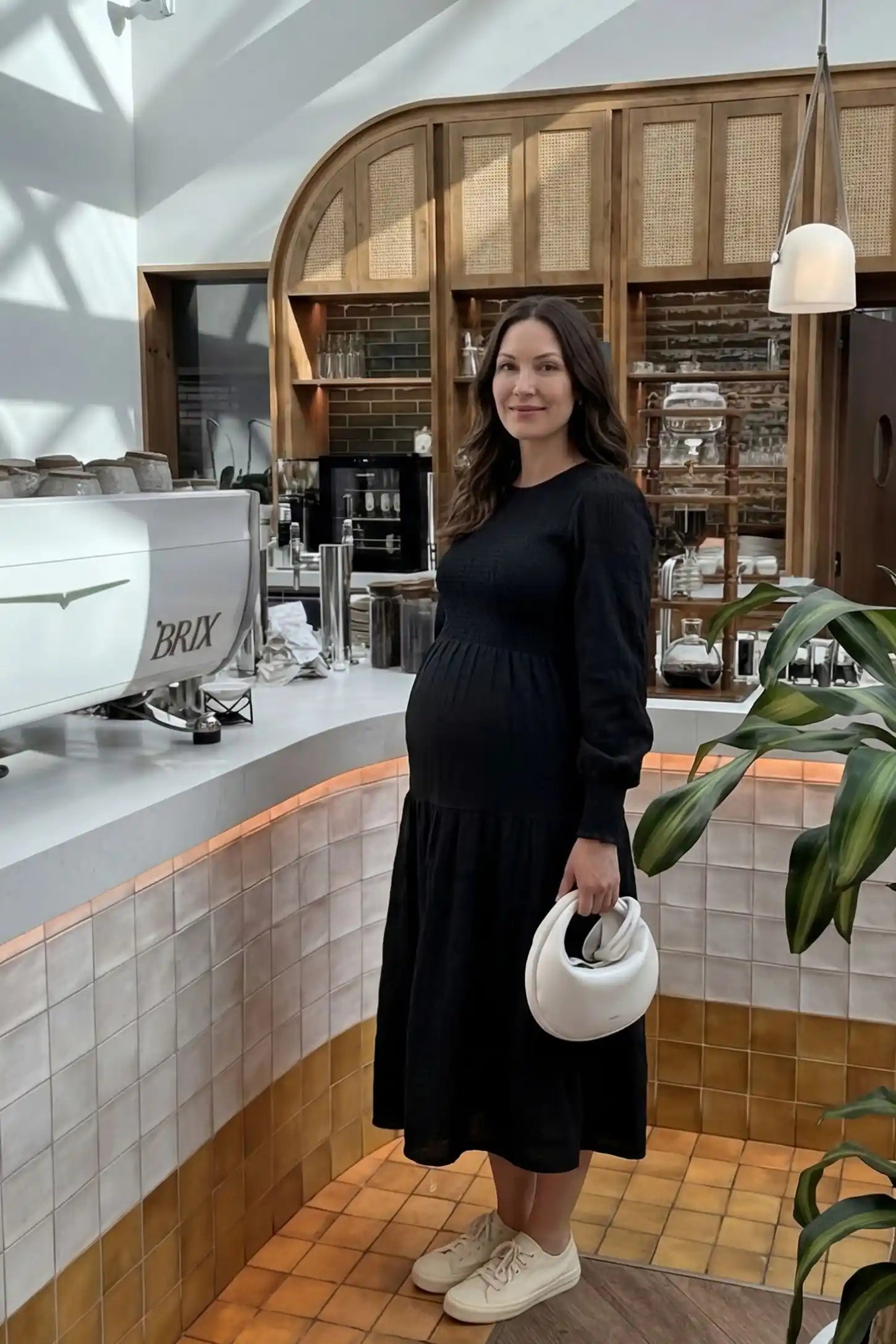 Solid Color Tiered Style Midi Maternity Dress Solid Color Tiered Style Midi Maternity Dress in black featuring a smocked bodice on a pregnant model, UGC view.