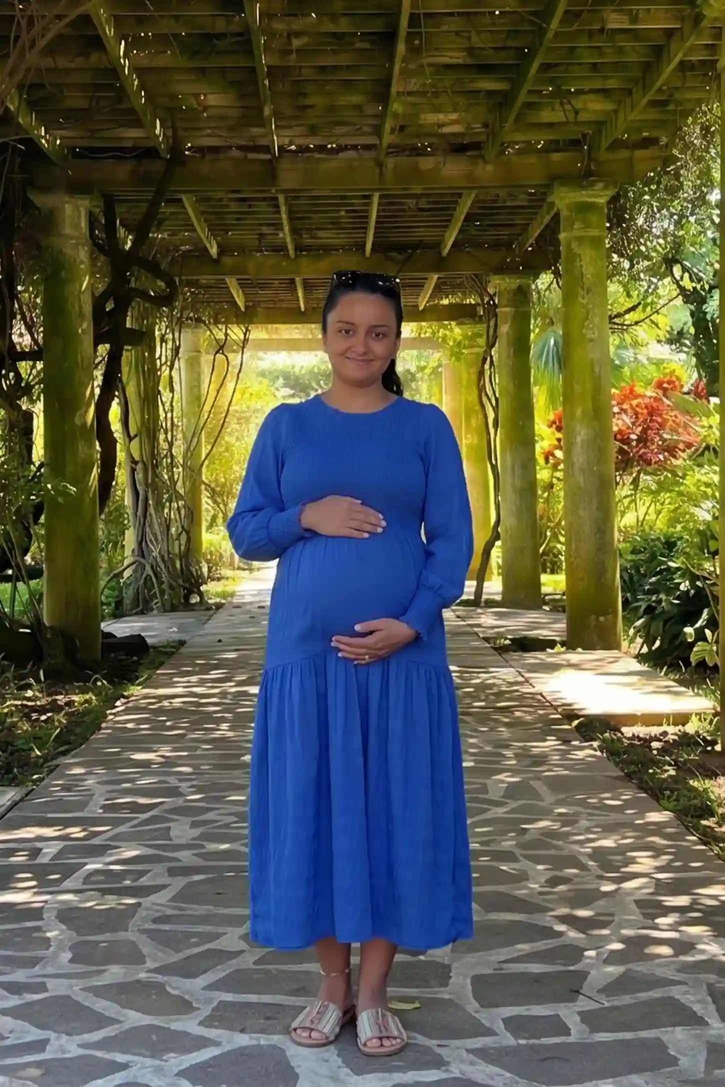 Solid Color Tiered Style Midi Maternity Dress Solid Color Tiered Style Midi Maternity Dress in blue featuring a smocked bodice on a pregnant model, UGC view.