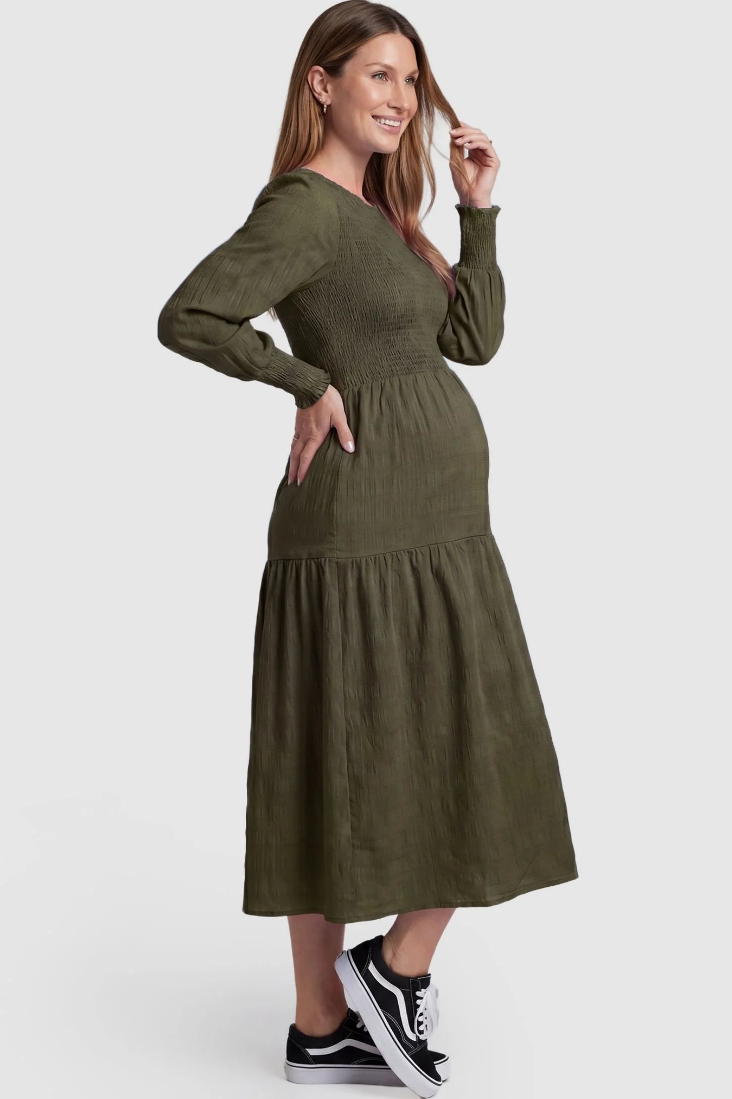 Solid Color Tiered Style Midi Maternity Dress Solid Color Tiered Style Midi Maternity Dress in green featuring a smocked bodice on a pregnant model, side view.
