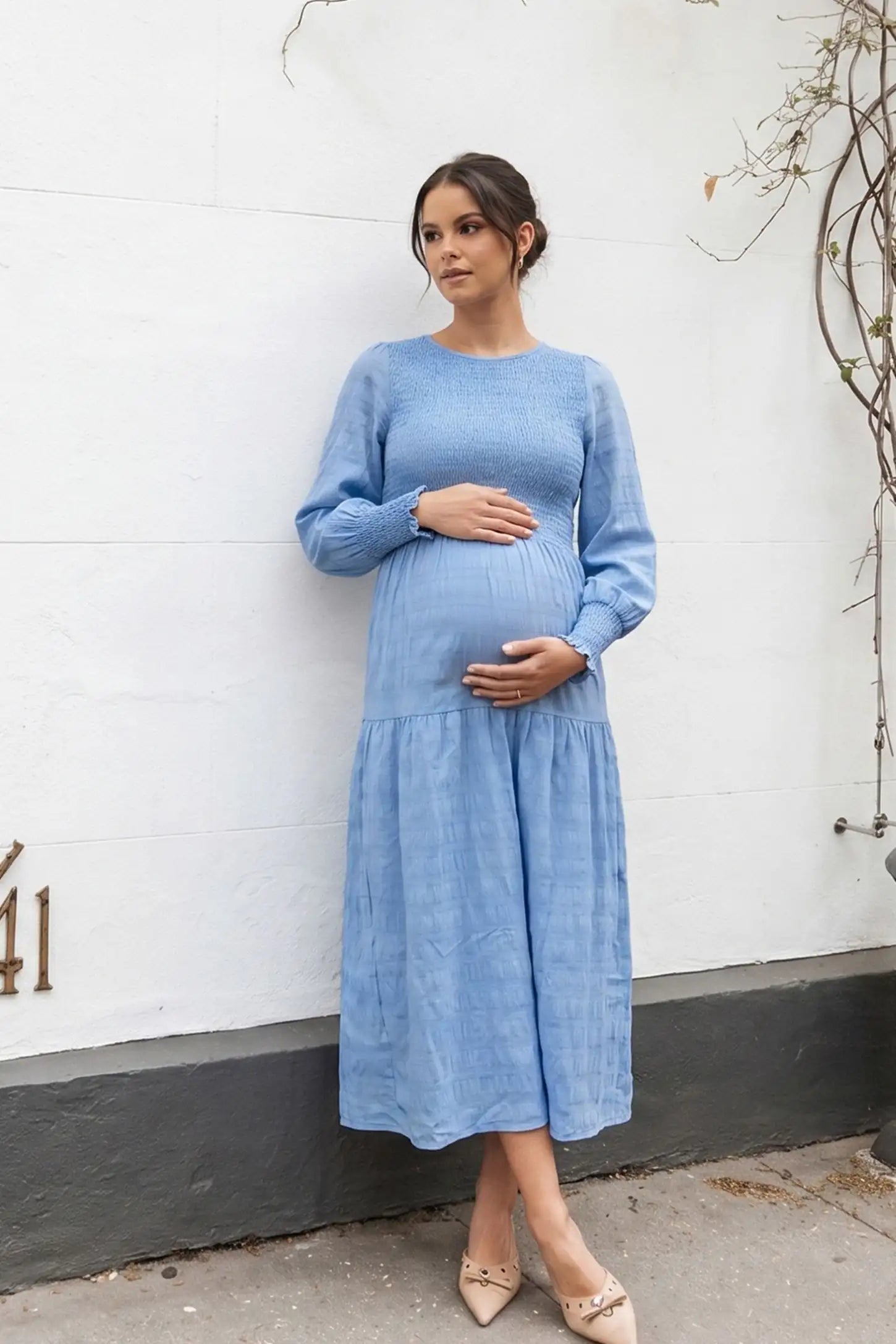 Solid Color Tiered Style Midi Maternity Dress Solid Color Tiered Style Midi Maternity Dress in light blue featuring a smocked bodice on a pregnant model, editorial lifestyle view.