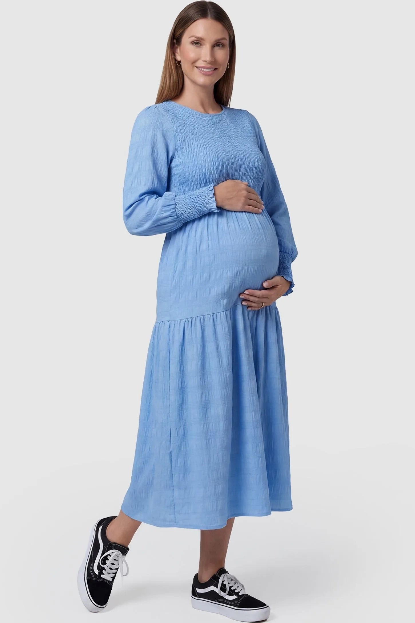 Solid Color Tiered Style Midi Maternity Dress Solid Color Tiered Style Midi Maternity Dress in light blue featuring a smocked bodice on a pregnant model, front view.