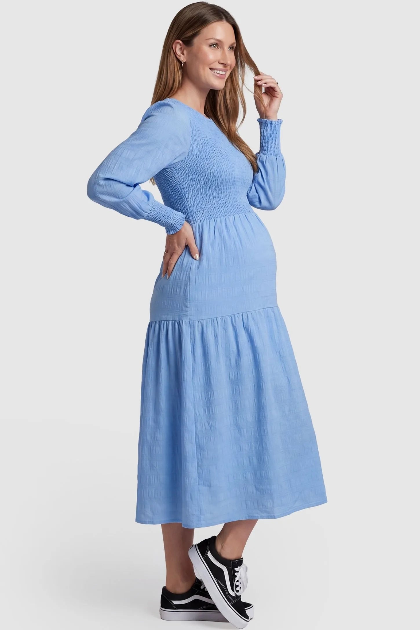 Solid Color Tiered Style Midi Maternity Dress Solid Color Tiered Style Midi Maternity Dress in light blue featuring a smocked bodice on a pregnant model, side view.