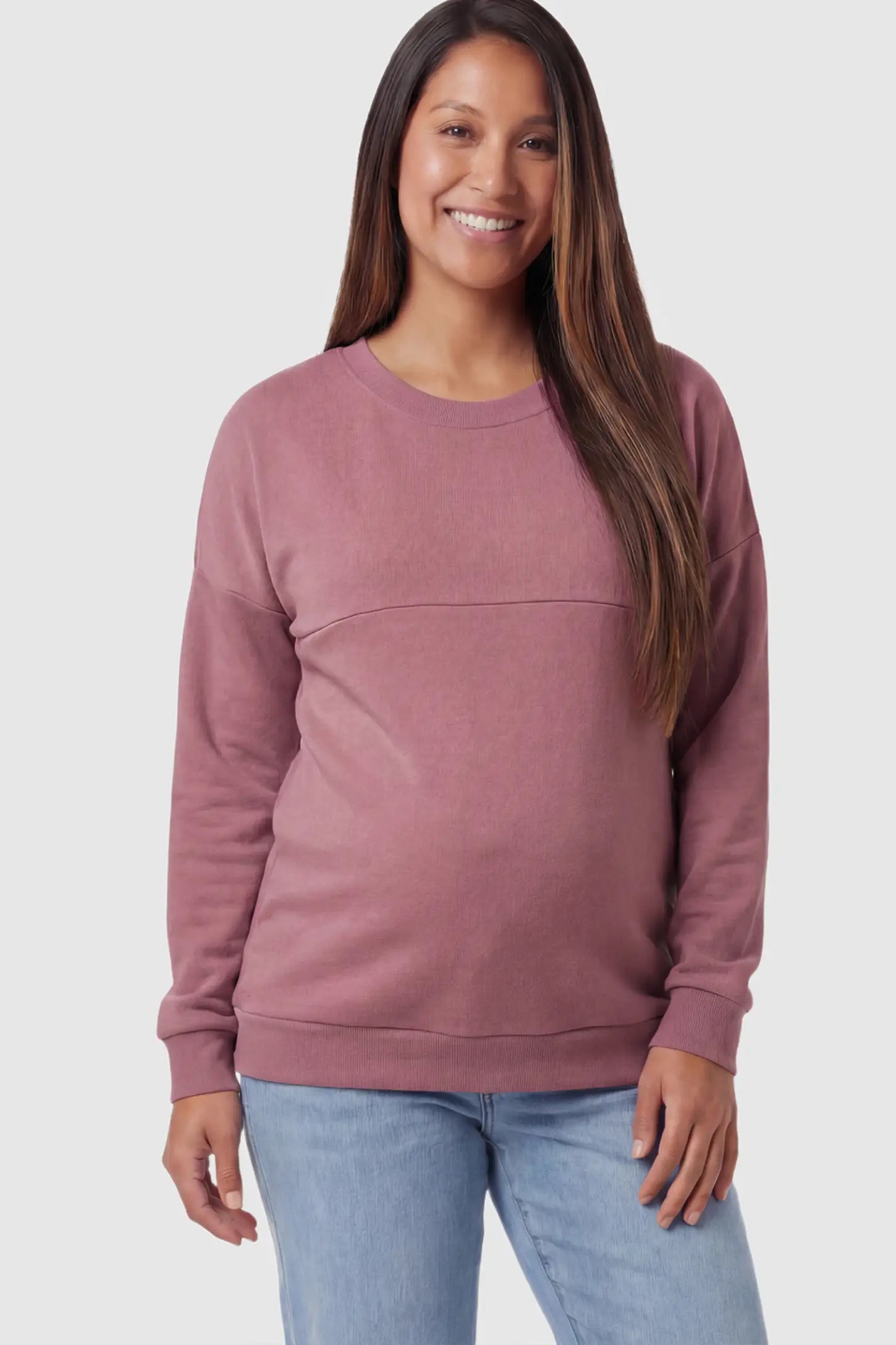 Solid Long Sleeve Maternity & Nursing Sweatshirt Solid Long Sleeve Maternity & Nursing Sweatshirt in Pink featuring a hidden zip raised seam on a pregnant model posing front.