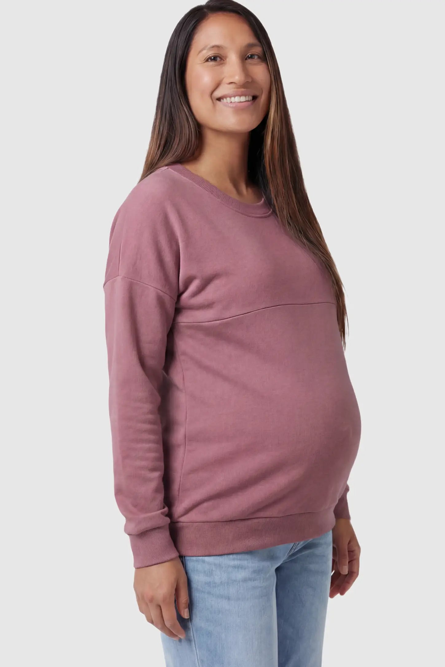 Solid Long Sleeve Maternity & Nursing Sweatshirt Solid Long Sleeve Maternity & Nursing Sweatshirt in Pink featuring a hidden zip raised seam on a pregnant model showing side.