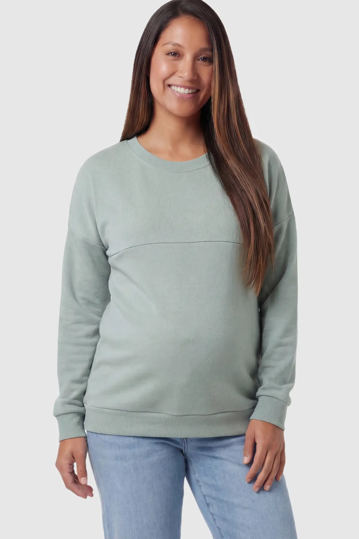 Solid Long Sleeve Maternity & Nursing Sweatshirt Solid Long Sleeve Maternity & Nursing Sweatshirt in Sage Green featuring a hidden zip raised seam on a pregnant model posing front.