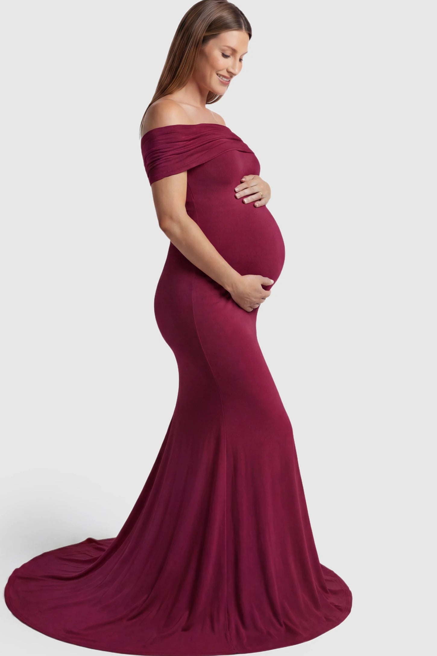 Solid Off Shoulder Maternity Photoshoot Gown Solid Off-Shoulder Maternity Photoshoot Gown in red featuring subtle train on a pregnant model showing side.