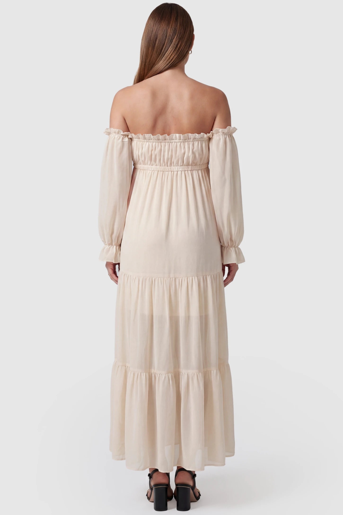 Solid Off Shoulder Tiered Maternity Maxi Dress Solid Off Shoulder Tiered Maternity Maxi Dress in beige featuring flowy tiered silhouette, Long Sleeve on a pregnant model, back view.