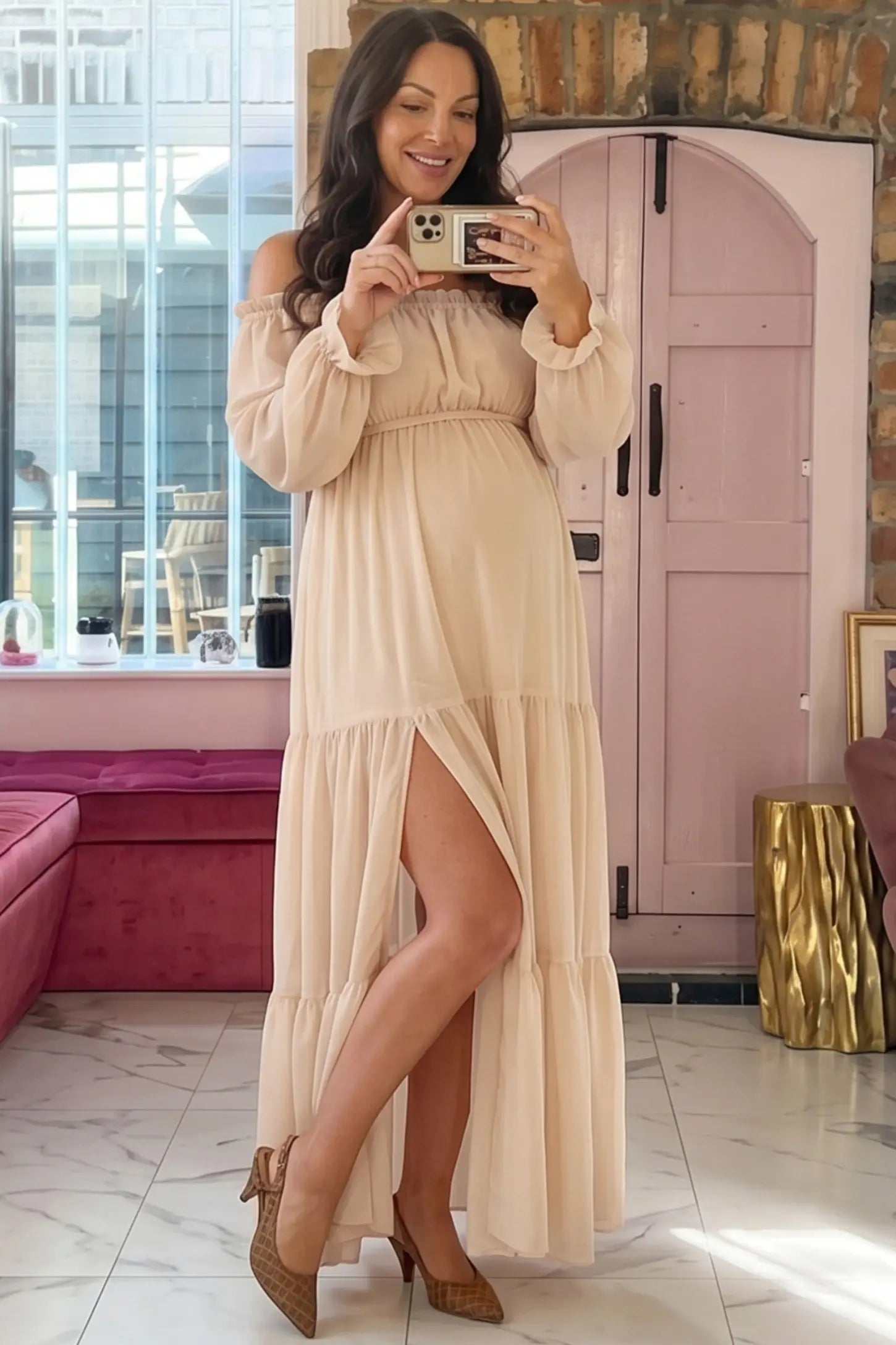 Solid Off Shoulder Tiered Maternity Maxi Dress Solid Off Shoulder Tiered Maternity Maxi Dress in beige featuring flowy tiered silhouette, Long Sleeve on a pregnant woman in indoor setting, front view.