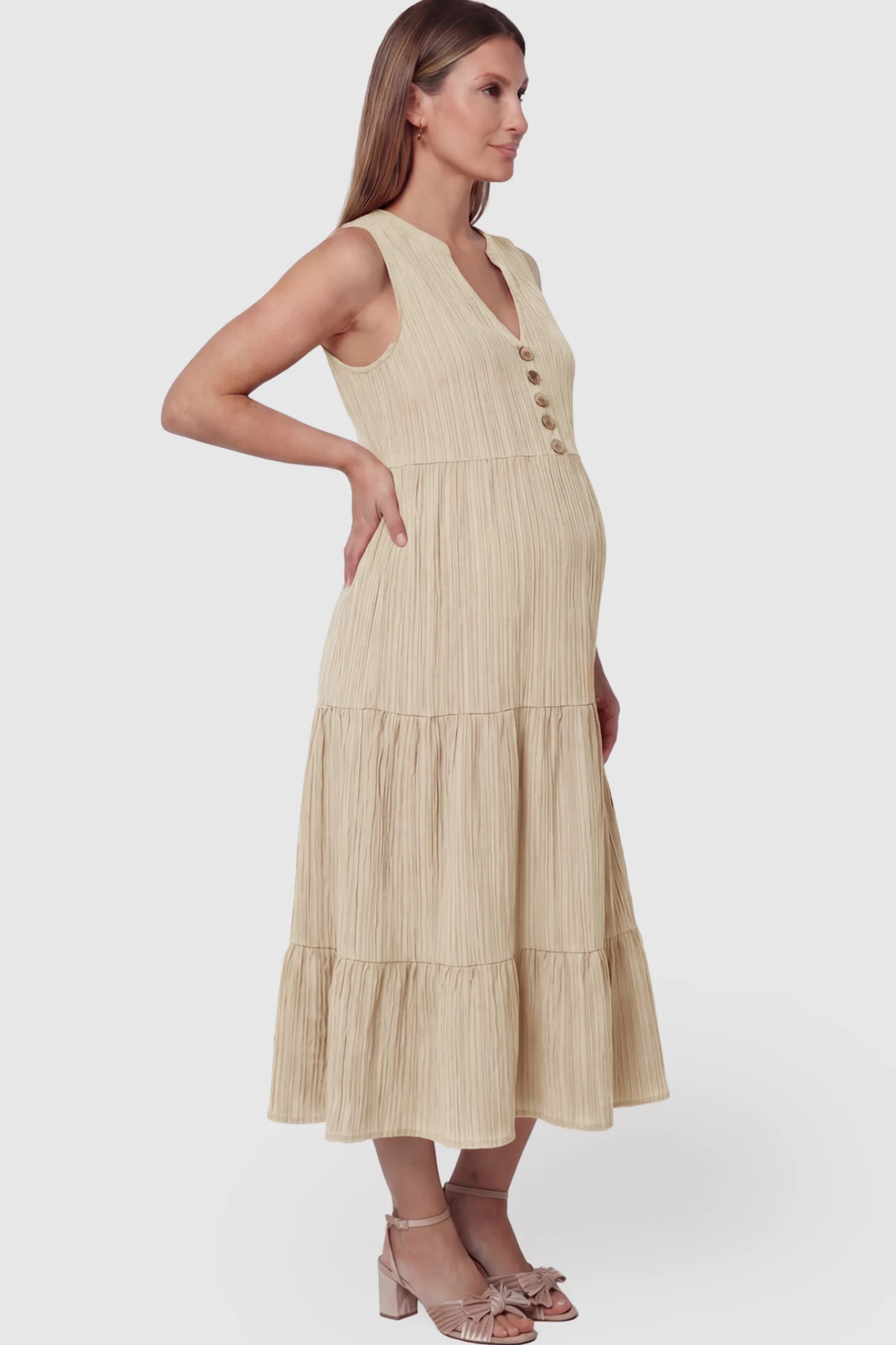 Solid Textured V-Neck Tiered Maternity Midi Dress Solid Textured V-Neck Tiered Maternity Midi Dress in Apricot featuring a high-waisted A-line silhouette on a pregnant model showing side.