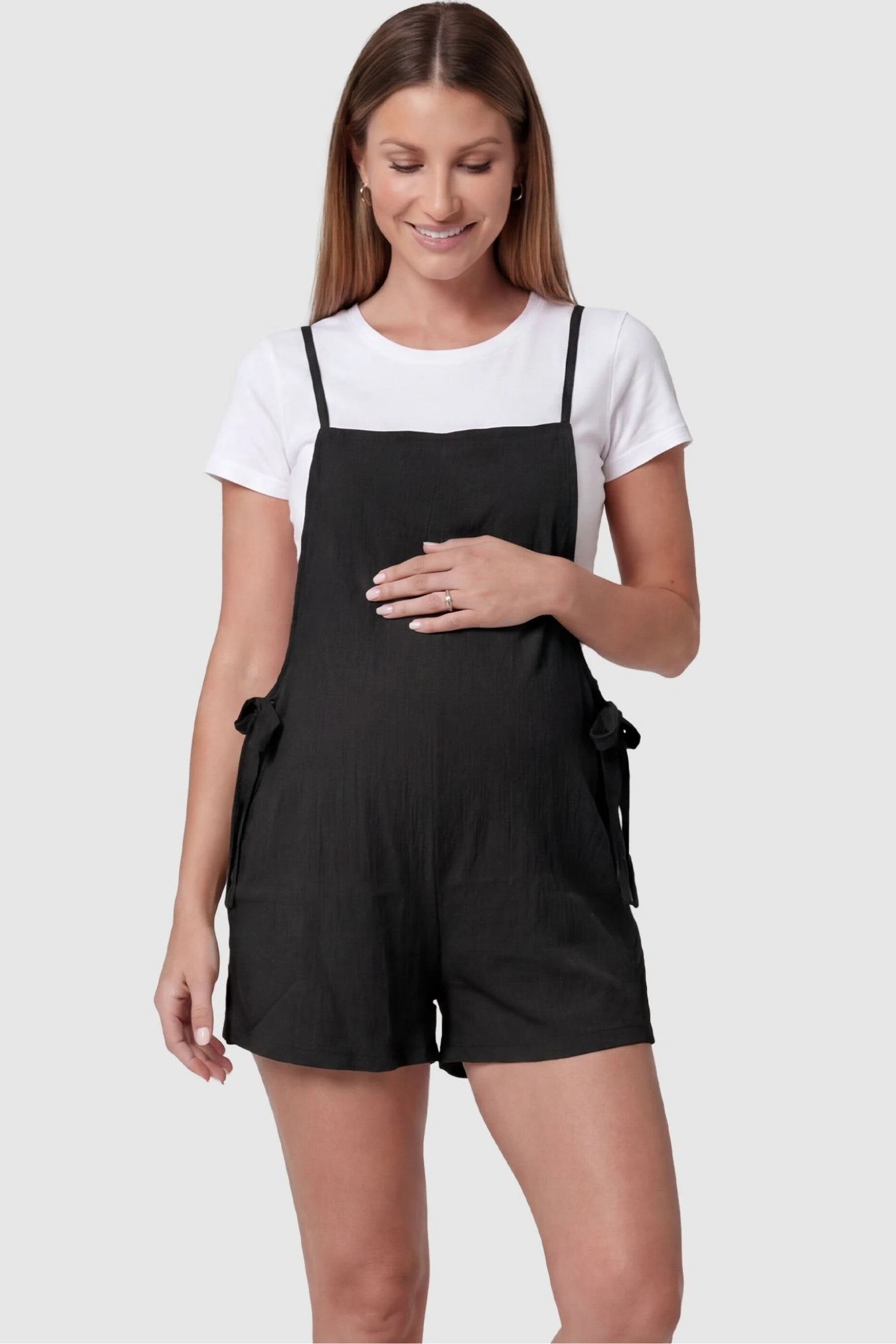 Spaghetti Strap Tie-Side Maternity Romper Spaghetti Strap Tie-Side Maternity Romper in Black featuring a square neckline on a front-facing pregnant model.