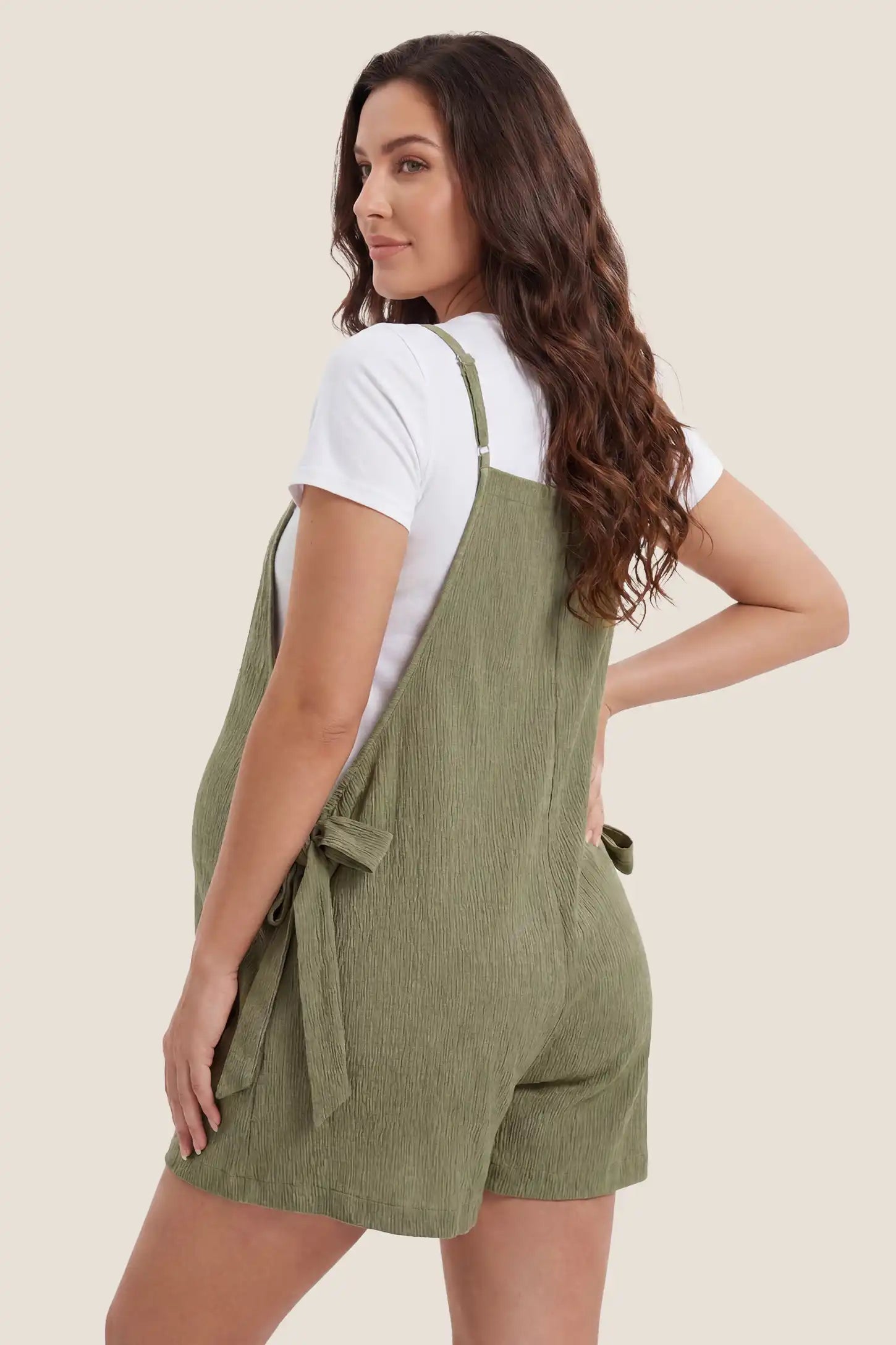 Rear view of Green Spaghetti Strap Tie-Side Maternity Romper featuring a straight-cut back and adjustable straps on a pregnant model.
