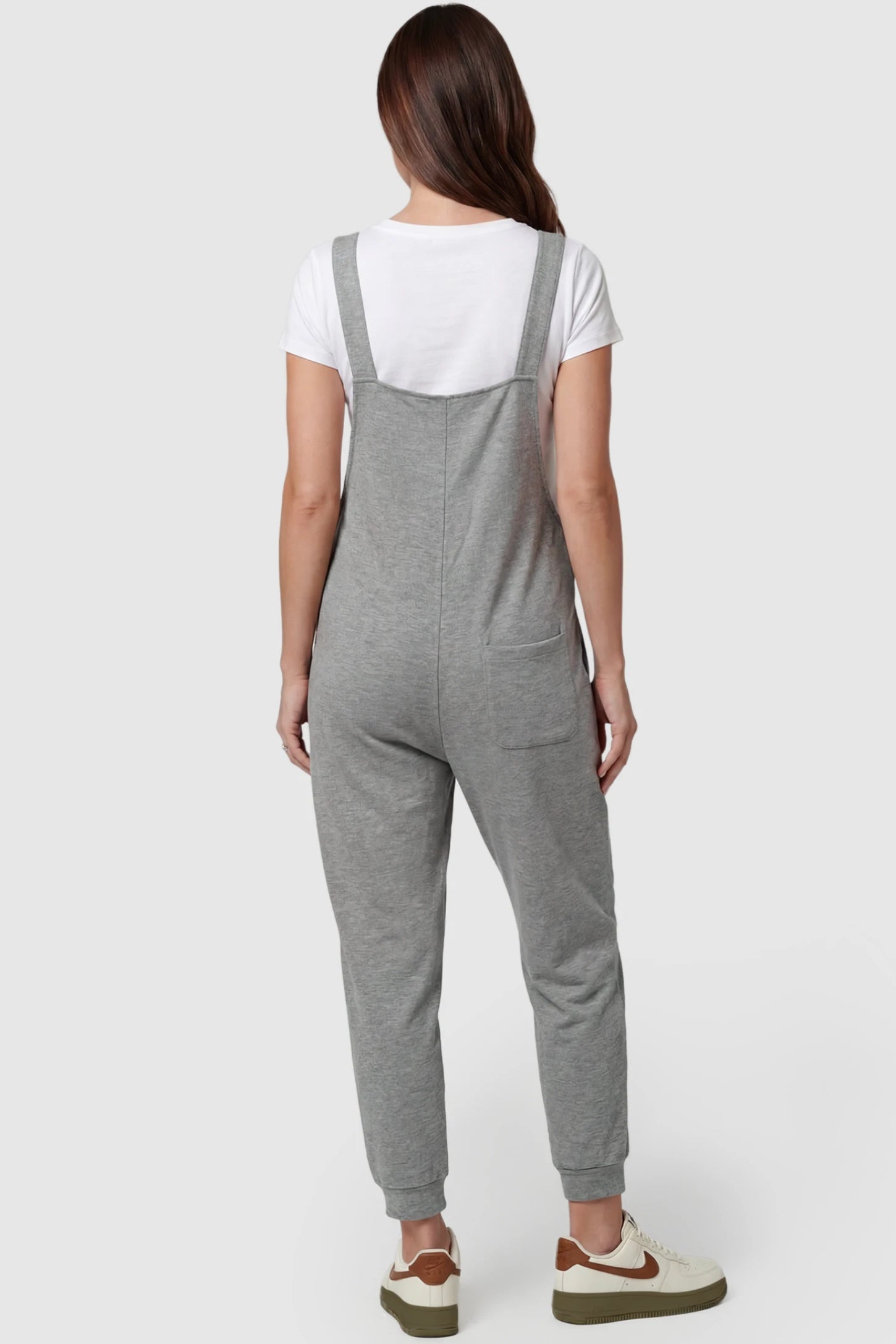 Square Neck Pocketed Maternity Jogger Jumpsuit Square Neck Pocketed Maternity Jogger Jumpsuit in gray featuring wide shoulder straps and patch pocket on a pregnant model, back view.