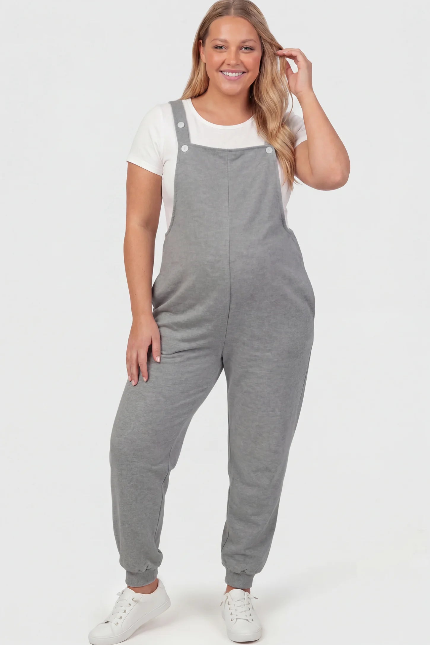 Square Neck Pocketed Maternity Jogger Jumpsuit Square Neck Pocketed Maternity Jogger Jumpsuit in gray featuring button straps on a plus size pregnant model, front view.