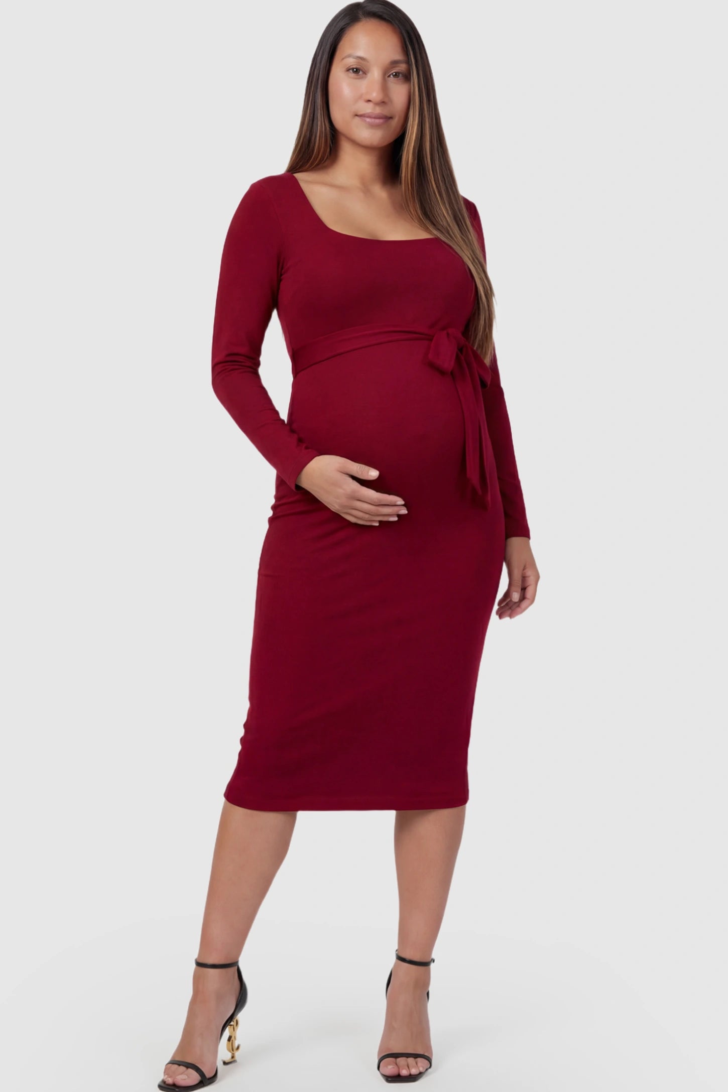 Square Neck Side-Tie Maternity Midi Dress Square Neck Side-Tie Maternity Midi Dress in Burgundy featuring a long-sleeve bodycon fit on a pregnant model posing front.