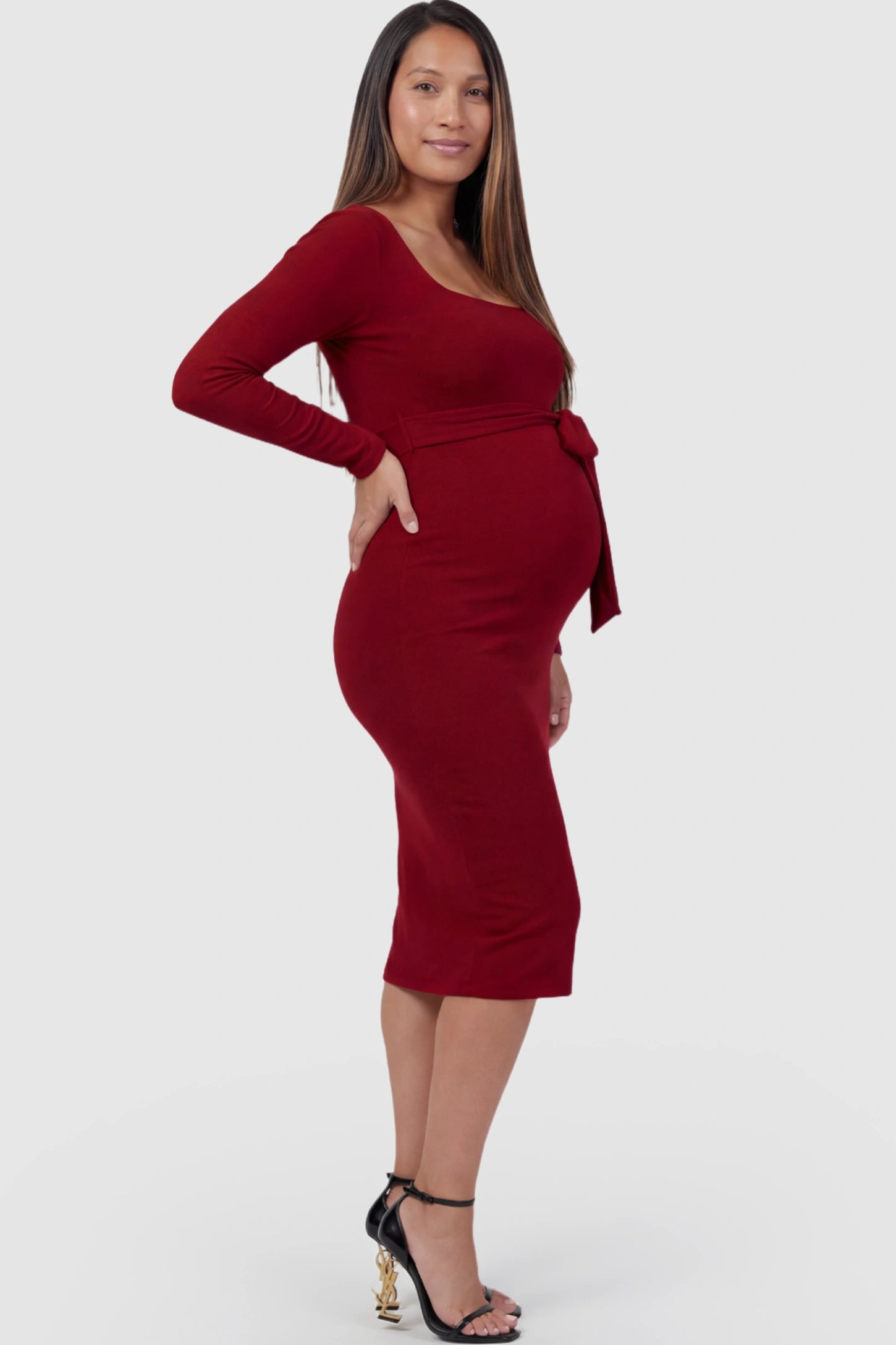 Square Neck Side-Tie Maternity Midi Dress Square Neck Side-Tie Maternity Midi Dress in Burgundy featuring a long-sleeve bodycon fit on a pregnant model showing side.