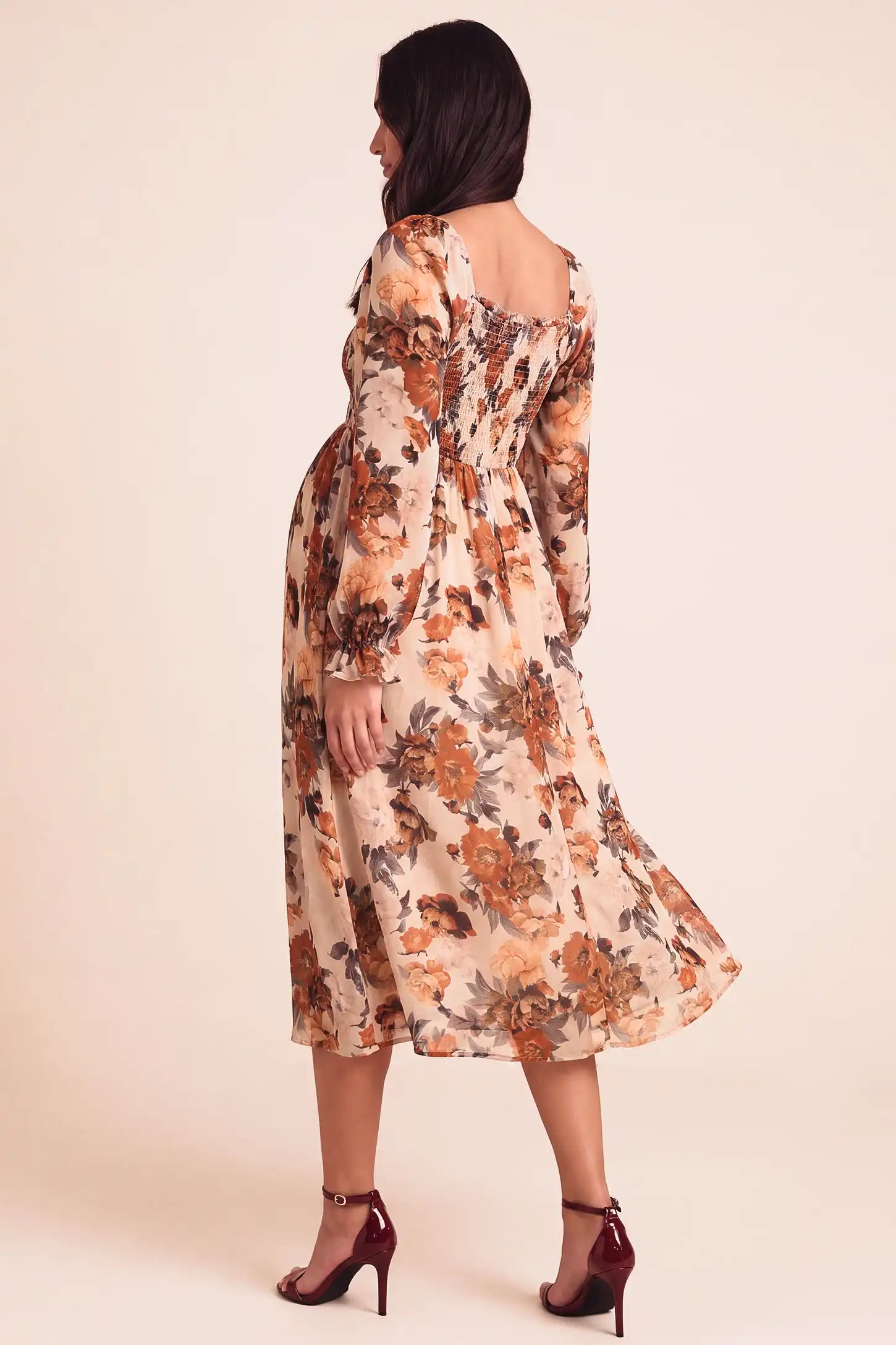 Square Neck Smocked Floral Maternity Midi Dress Square Neck Smocked Floral Maternity Midi Dress in Rust Floral showcasing smocked back and long sleeves on a pregnant model, studio back view.