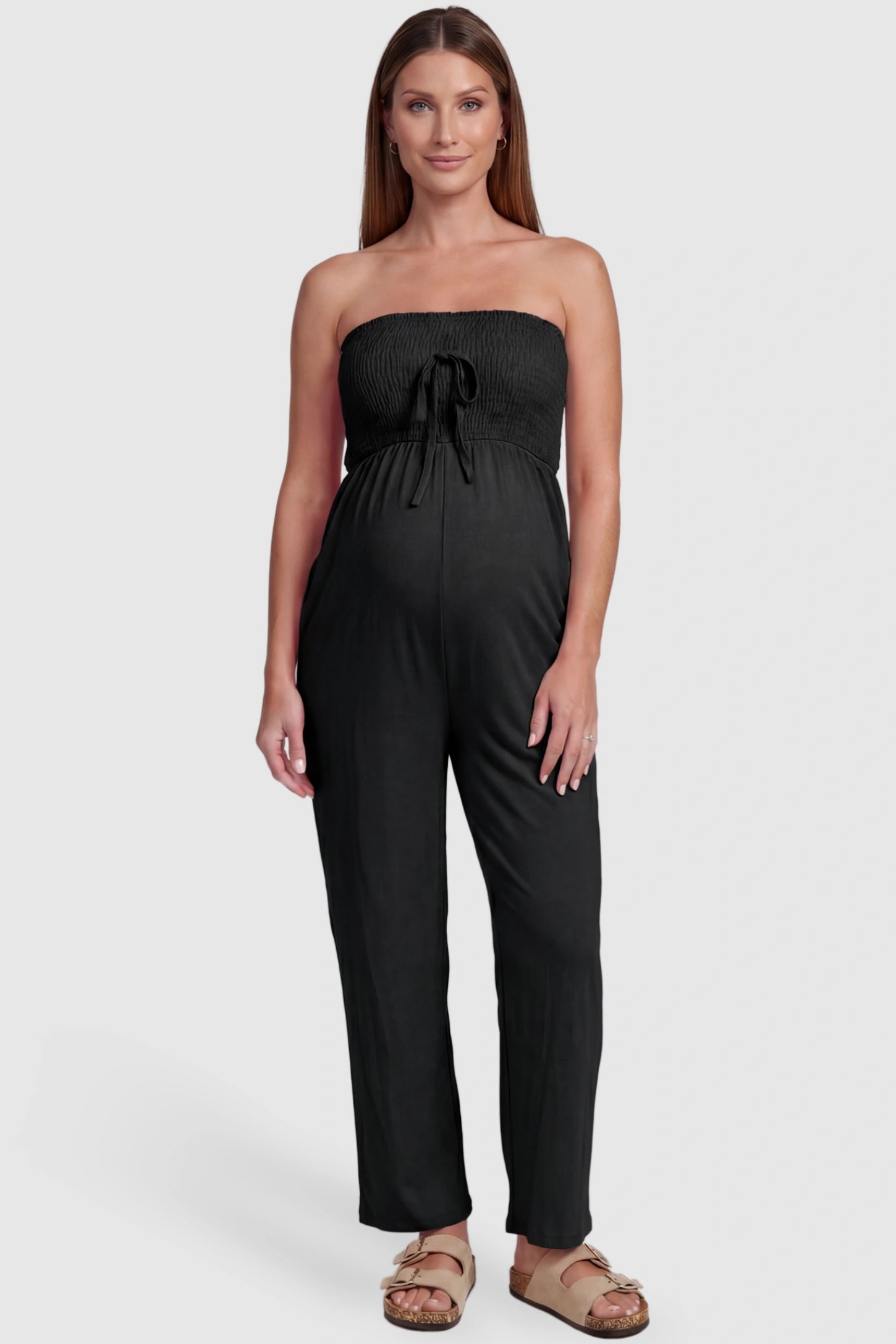 Strapless Smocked Bust Wide Leg Maternity Jumpsuit Strapless Smocked Bust Wide Leg Maternity Jumpsuit in Black featuring a relaxed leg design on a pregnant model, front view.