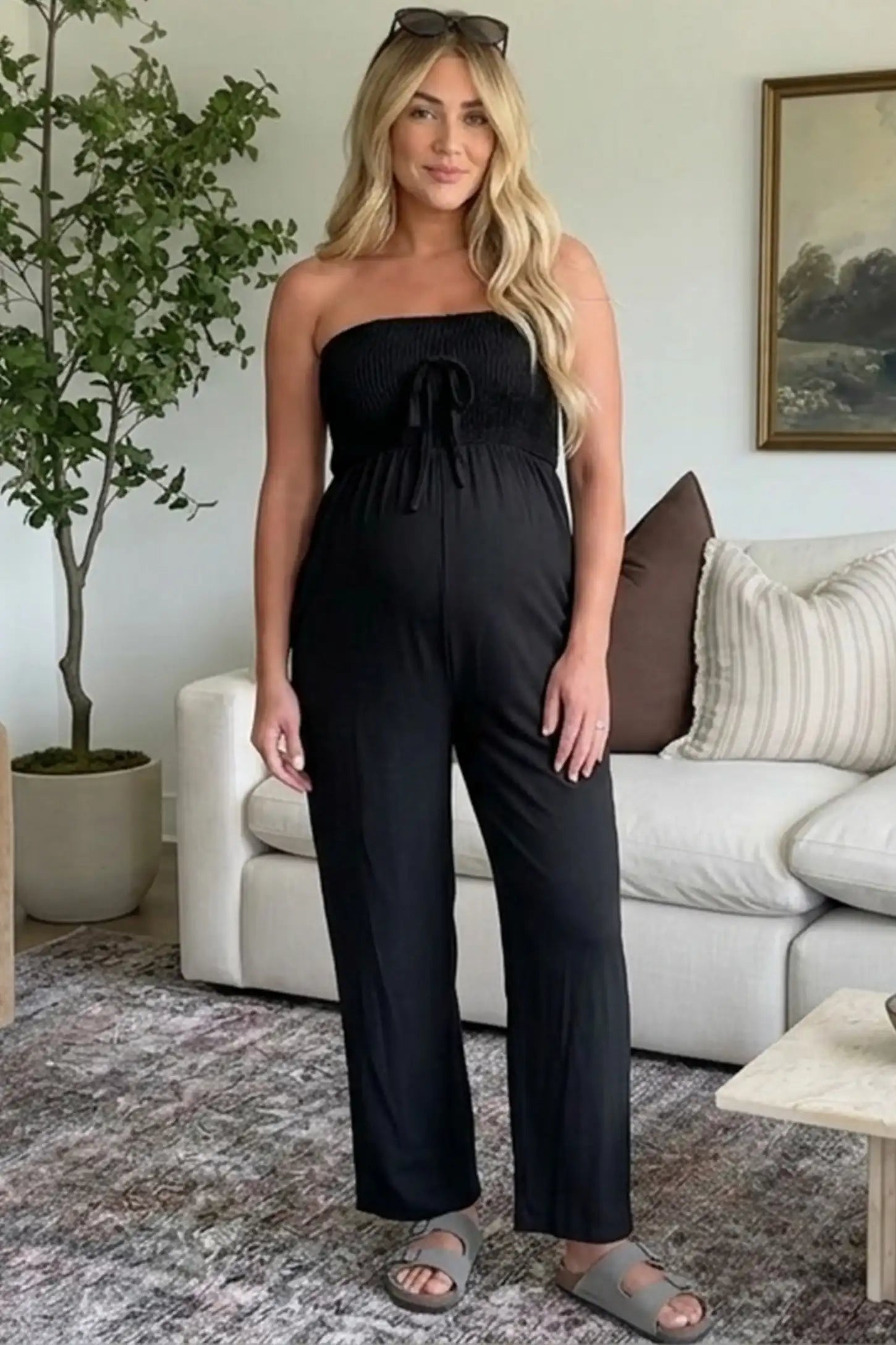 Strapless Smocked Bust Wide Leg Maternity Jumpsuit Strapless Smocked Bust Wide Leg Maternity Jumpsuit in Black featuring a relaxed leg design on a pregnant woman in outdoor setting, front view.