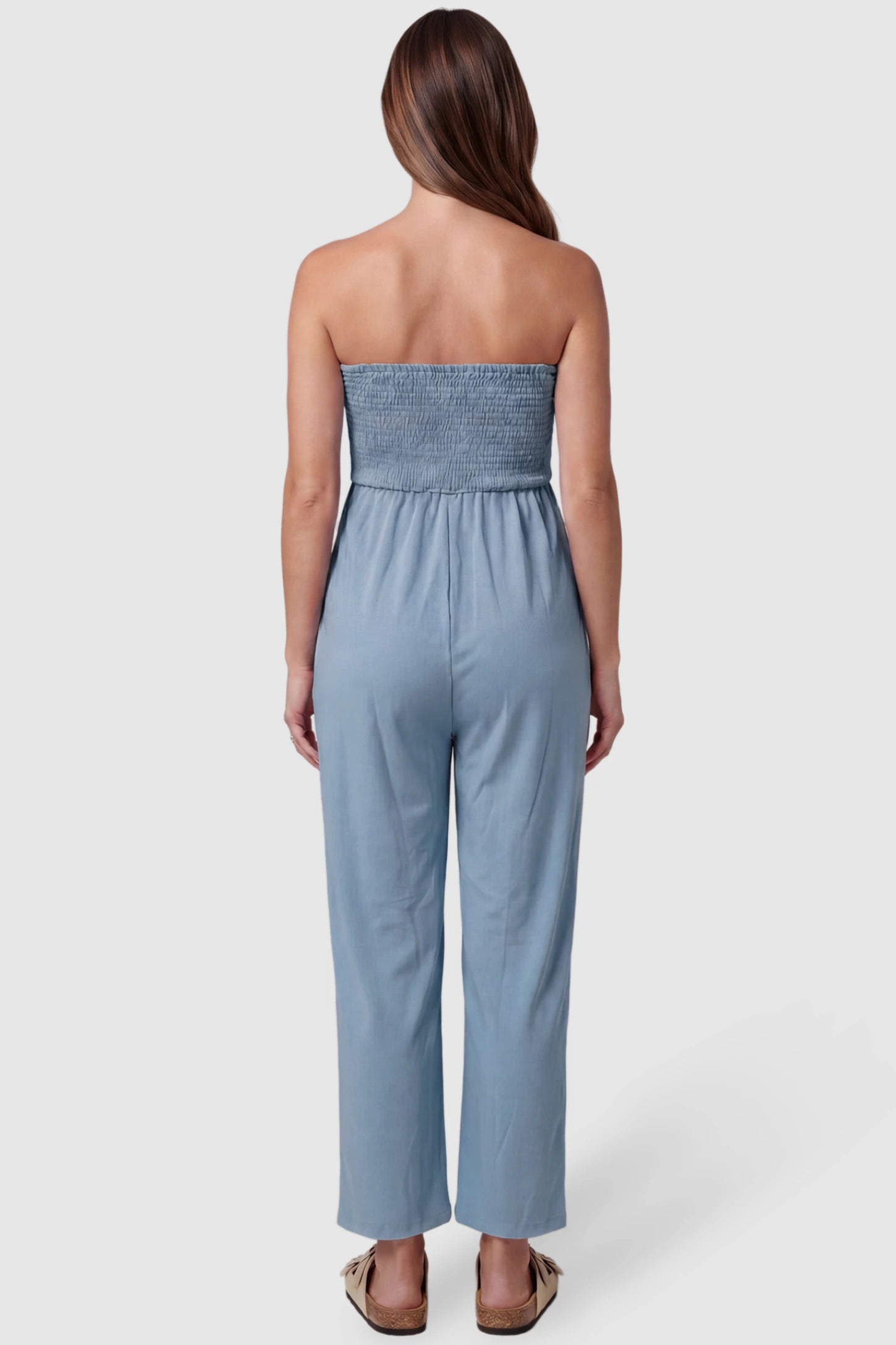 Strapless Smocked Bust Wide Leg Maternity Jumpsuit Strapless Smocked Bust Wide Leg Maternity Jumpsuit in Blue featuring a relaxed leg design on a pregnant model, back view.