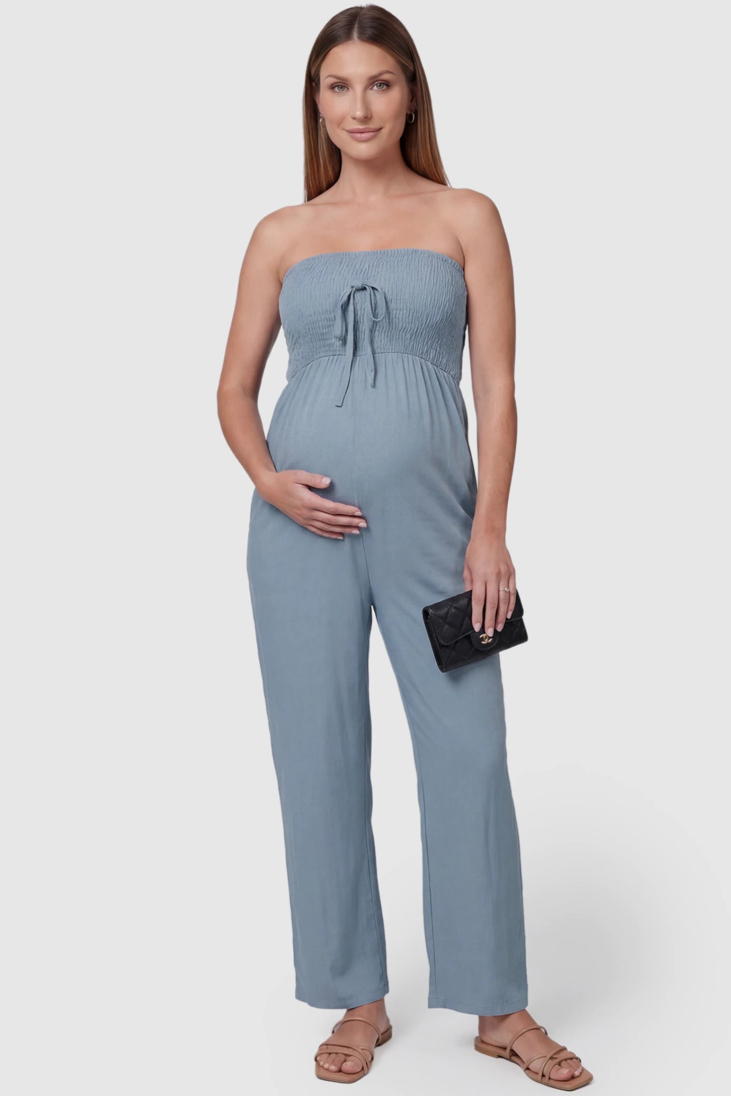Strapless Smocked Bust Wide Leg Maternity Jumpsuit Strapless Smocked Bust Wide Leg Maternity Jumpsuit in Blue featuring a relaxed leg design on a pregnant model, front view.