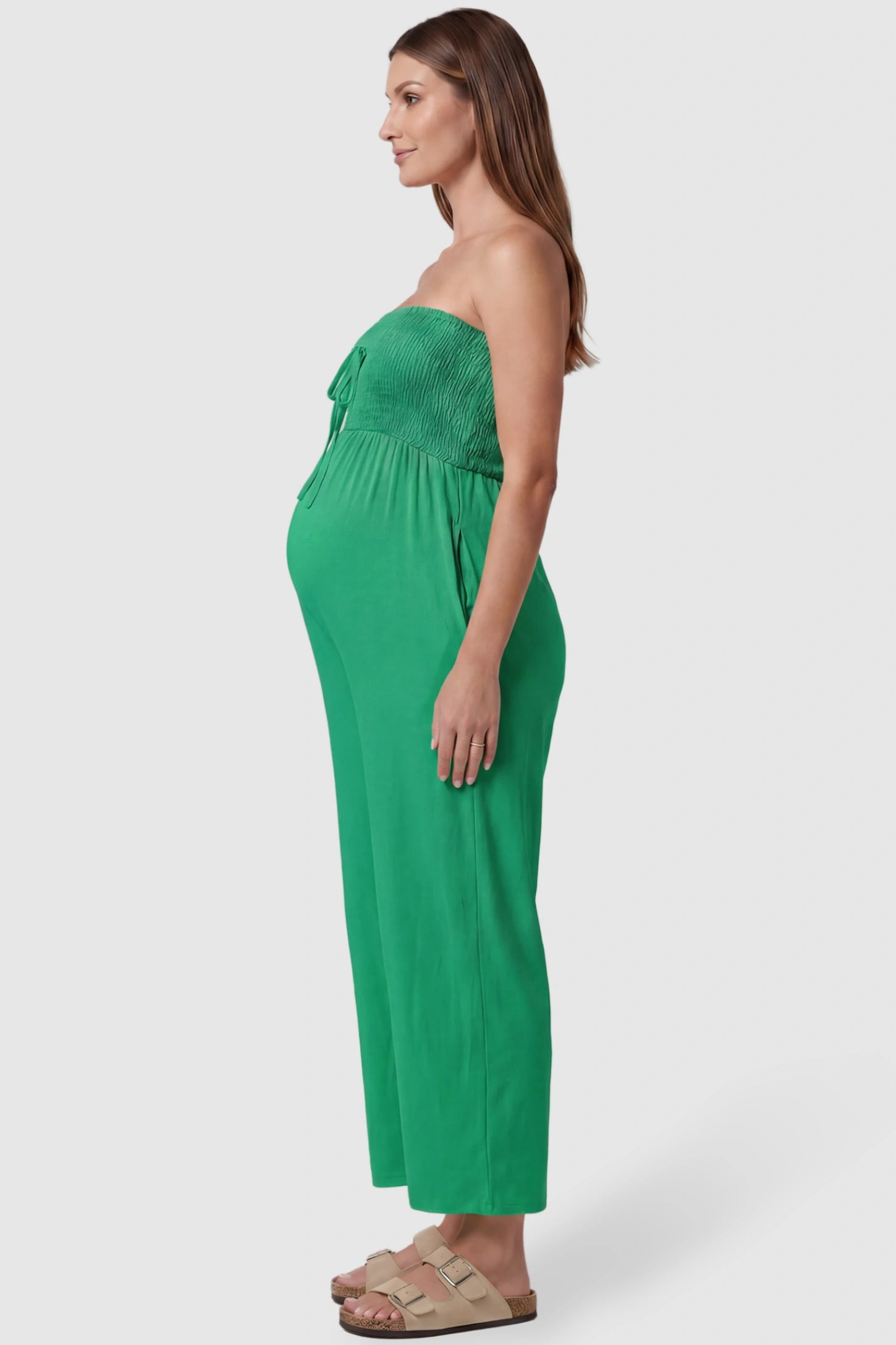 Strapless Smocked Bust Wide Leg Maternity Jumpsuit Strapless Smocked Bust Wide Leg Maternity Jumpsuit in Green featuring a relaxed leg design on a pregnant model, side view.