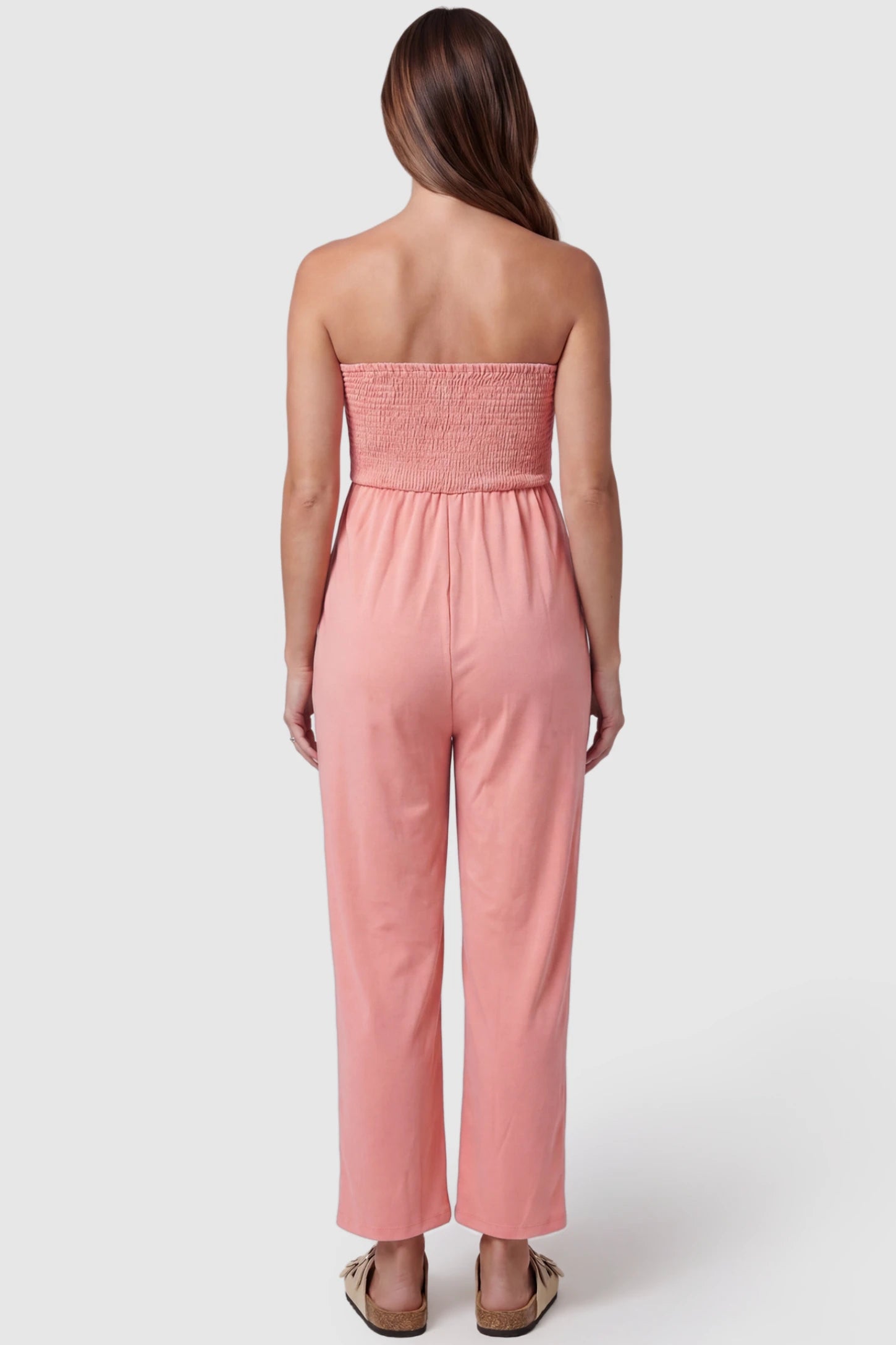 Strapless Smocked Bust Wide Leg Maternity Jumpsuit Strapless Smocked Bust Wide Leg Maternity Jumpsuit in Pink featuring a relaxed leg design on a pregnant model, back view.