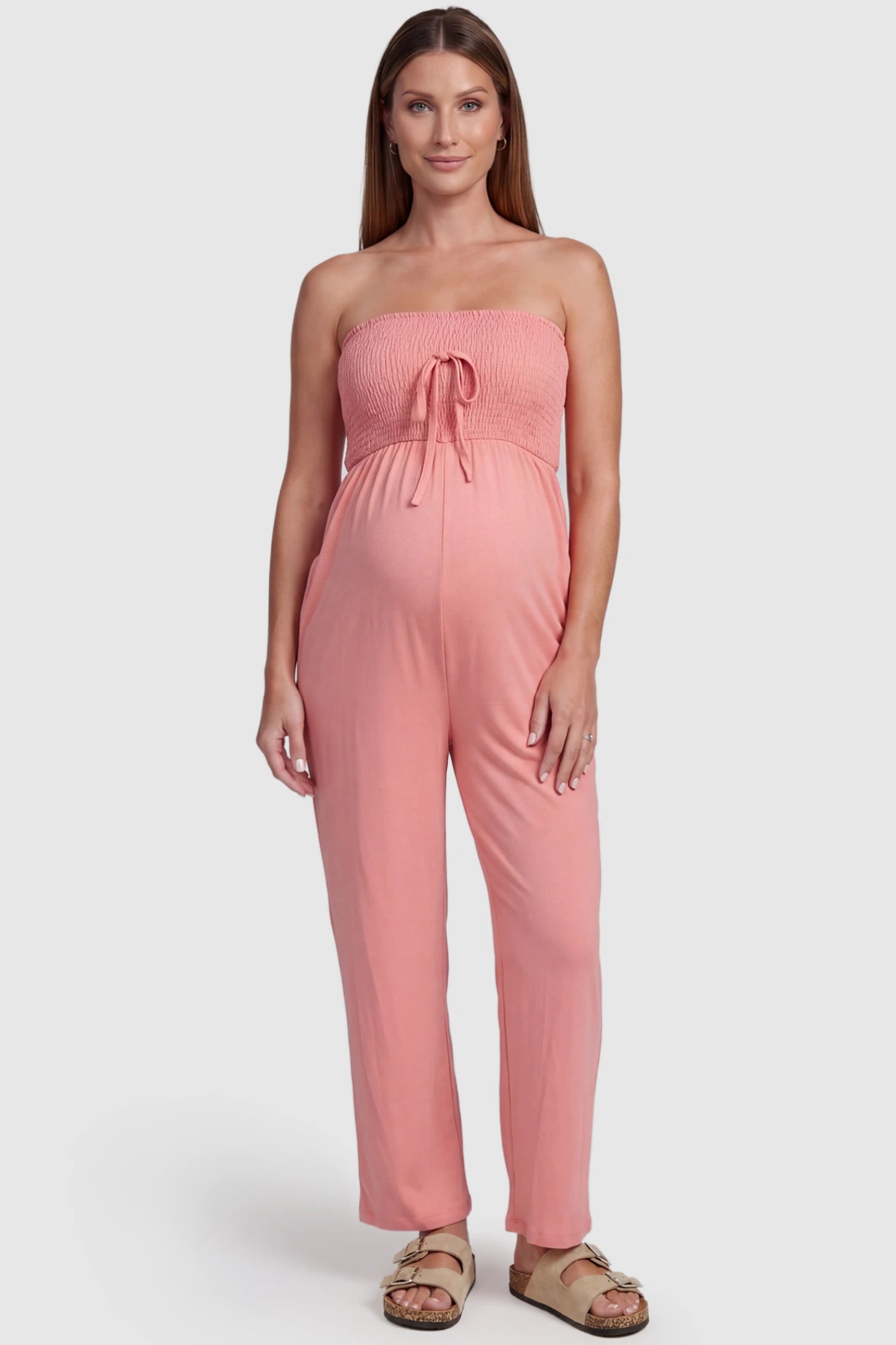 Strapless Smocked Bust Wide Leg Maternity Jumpsuit in Pink featuring a relaxed leg design on a pregnant model, front view.