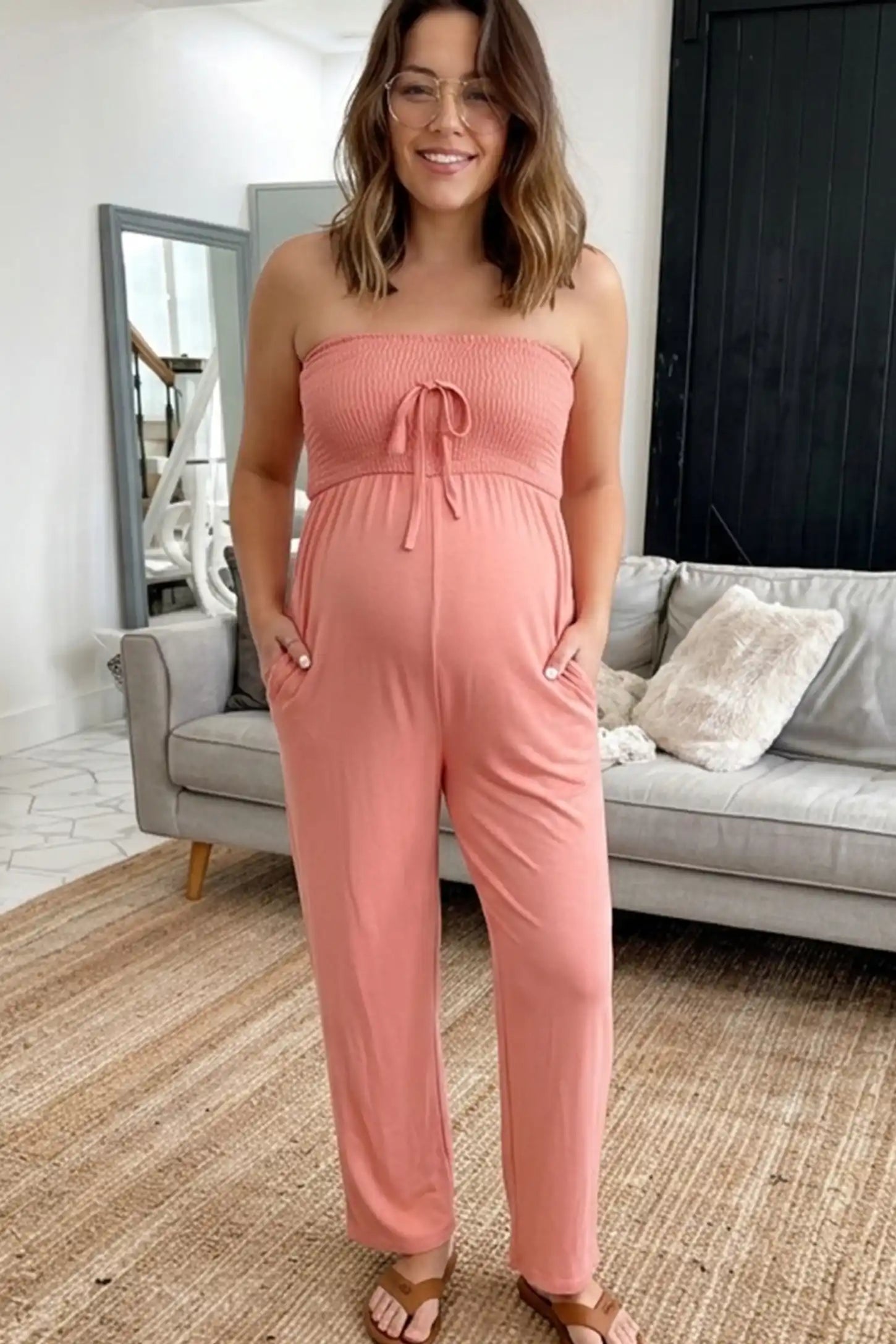 Strapless Smocked Bust Wide Leg Maternity Jumpsuit Strapless Smocked Bust Wide Leg Maternity Jumpsuit in Pink featuring a relaxed leg design on a pregnant woman in indoor setting, front view.