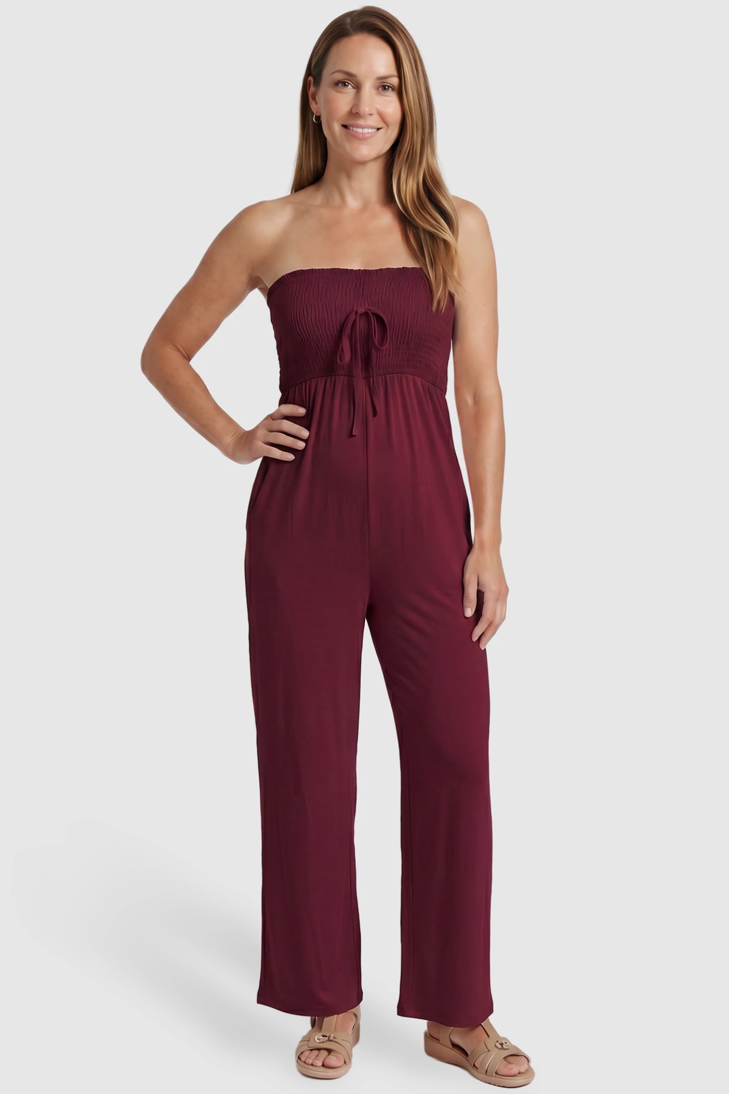 Strapless Smocked Bust Wide Leg Maternity Jumpsuit Strapless Smocked Bust Wide Leg Maternity Jumpsuit in Wine Red featuring a relaxed leg design on a postpartum model, front view.