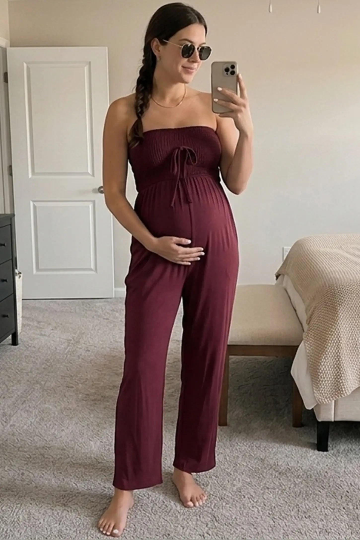 Strapless Smocked Bust Wide Leg Maternity Jumpsuit Strapless Smocked Bust Wide Leg Maternity Jumpsuit in Wine Red featuring a relaxed leg design on a pregnant woman in outdoor setting, front view.